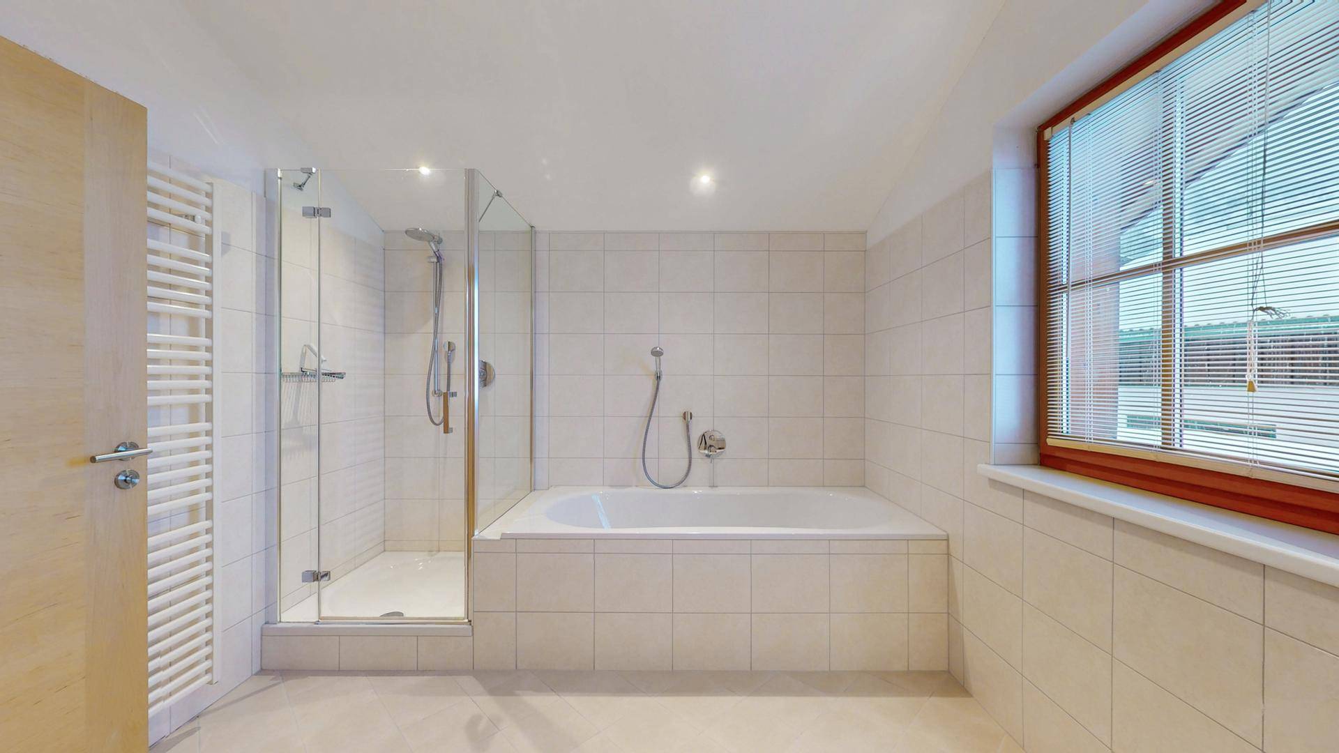 Geräumiges Badezimmer mit Badewanne, Duschkabine und beheiztem Handtuchhalter.