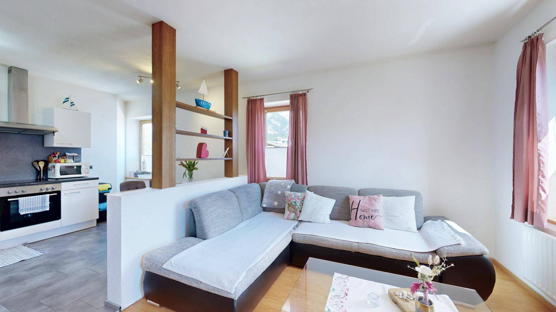 Gemütlicher Wohnbereich mit Ecksofa und offener Verbindung zur Küche, ideal für geselliges Beisammensein.