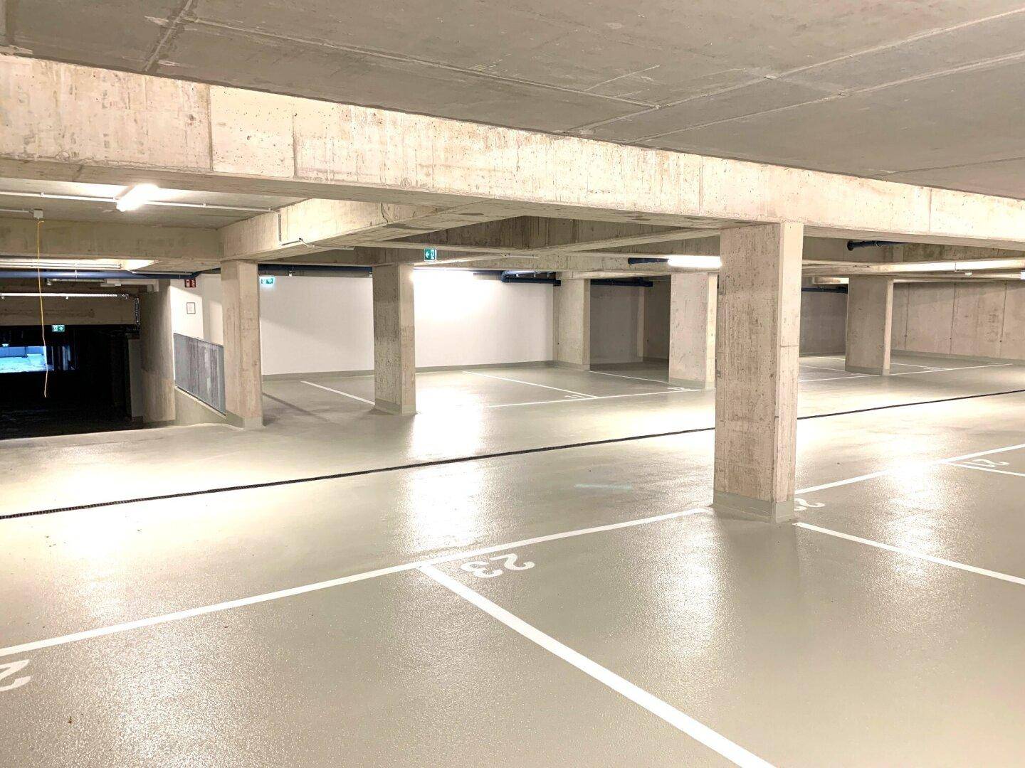 Weitläufige Tiefgarage mit vielen Stellplätzen und klarer Beschilderung.