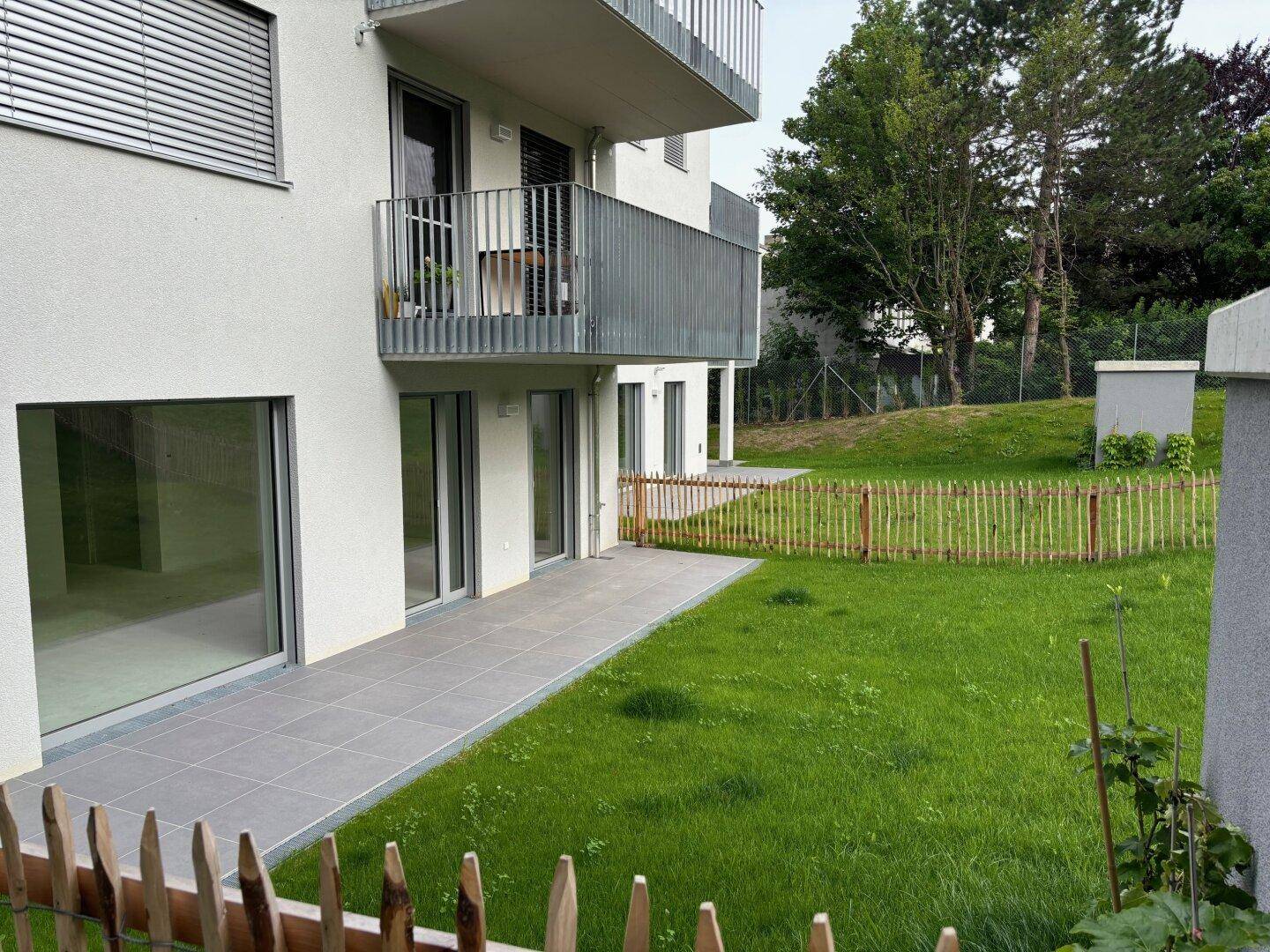 Erdgeschosswohnung mit großer gefliester Terrasse und direktem Zugang zur grünen Rasenfläche.
