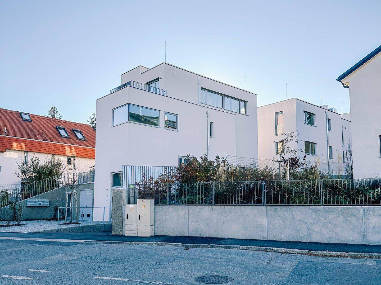Moderne Wohnanlage mit klarer Architektur und Flachdach, gut integriert in die Umgebung.