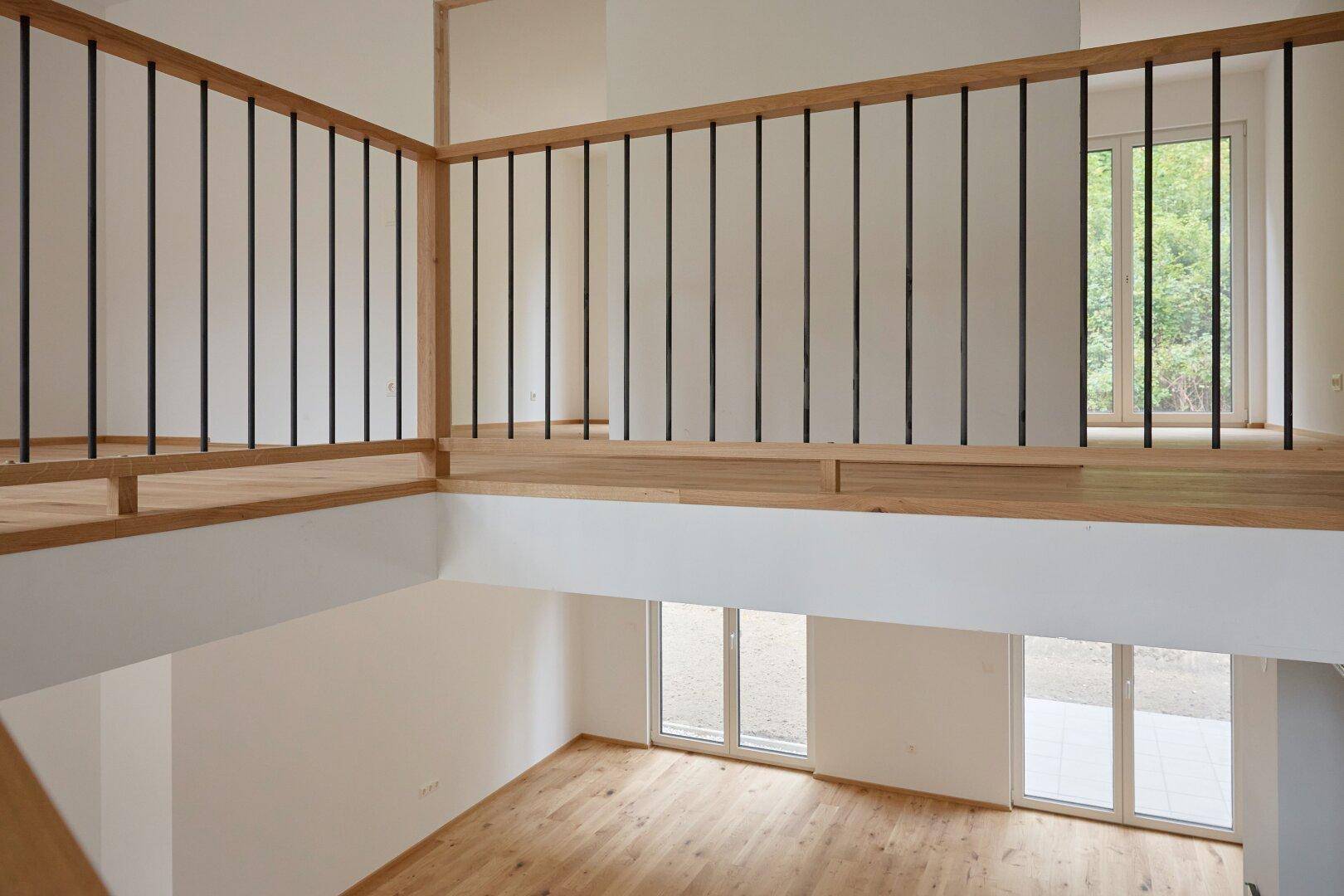 Offene Galerie im Obergeschoss mit Holzgeländer und Blick in den darunterliegenden Wohnbereich.