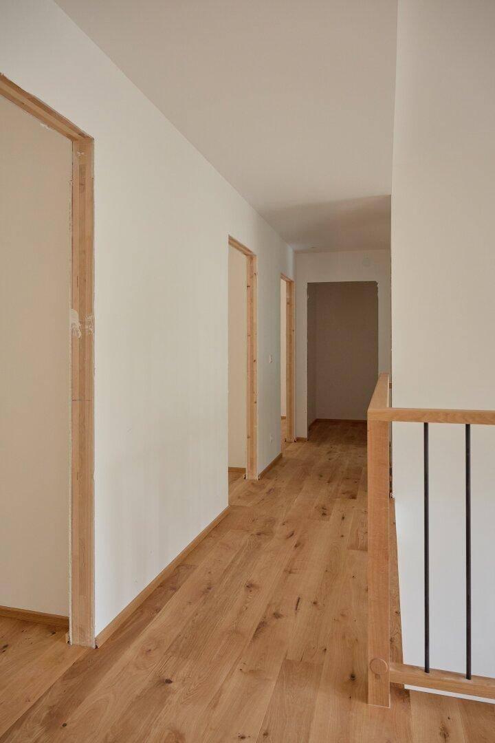 Langer, heller Flur mit Eichenparkett und Türrahmen, der zu weiteren Räumen führt.