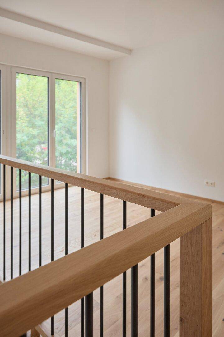 Modernes Holzgeländer mit schwarzen Stäben im Obergeschoss, das den offenen Bereich sichert.