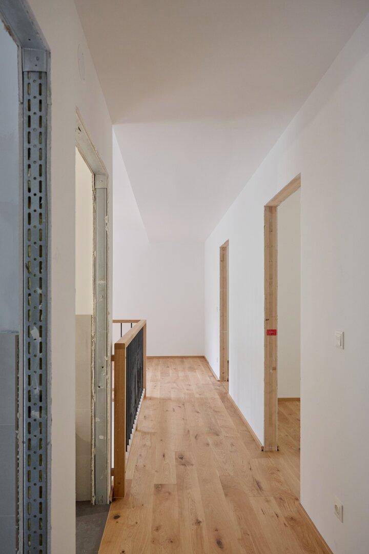 Geräumiger Flur mit hellem Holzboden und Blick auf die Treppe sowie weitere Zimmer.