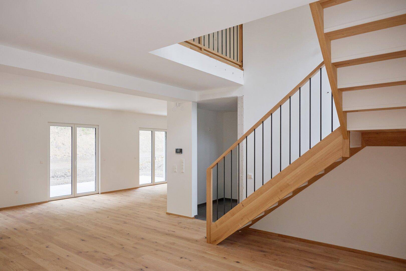 Heller Wohnbereich mit Eichenparkett und moderner Holztreppe, die ins obere Stockwerk führt.