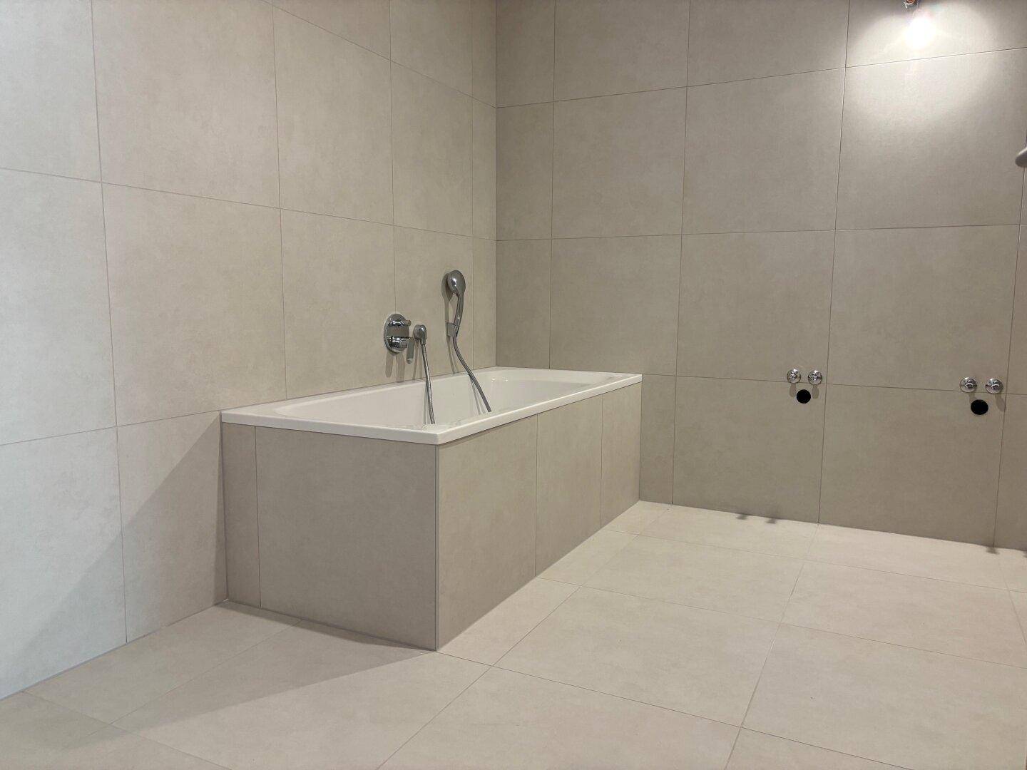 Geräumiges Badezimmer mit integrierter Badewanne und modernen Fliesen, bereit für die Fertigstellung.