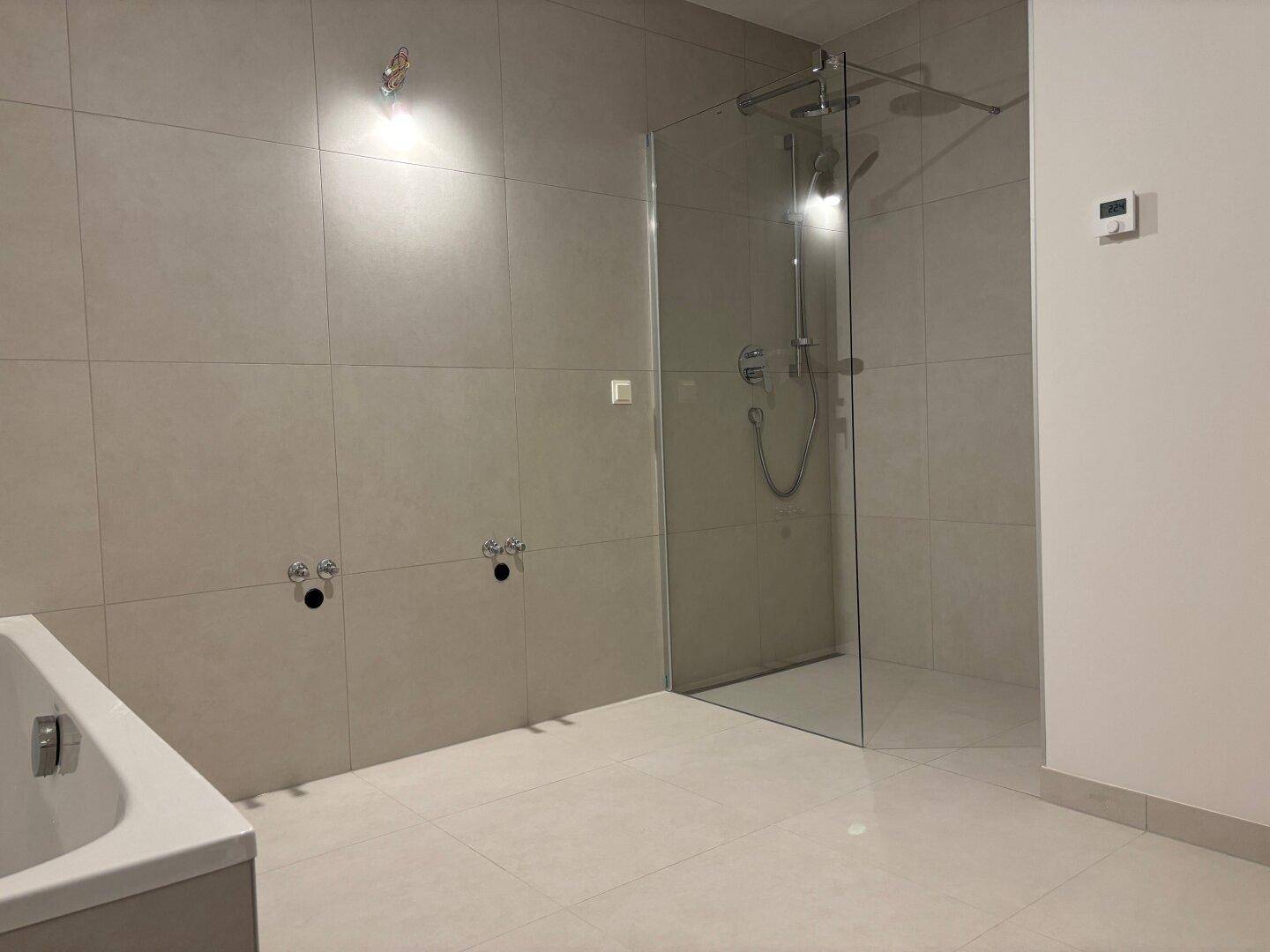 Modernes Badezimmer mit Badewanne und begehbarer Dusche, noch ohne Armaturen und Möbel.