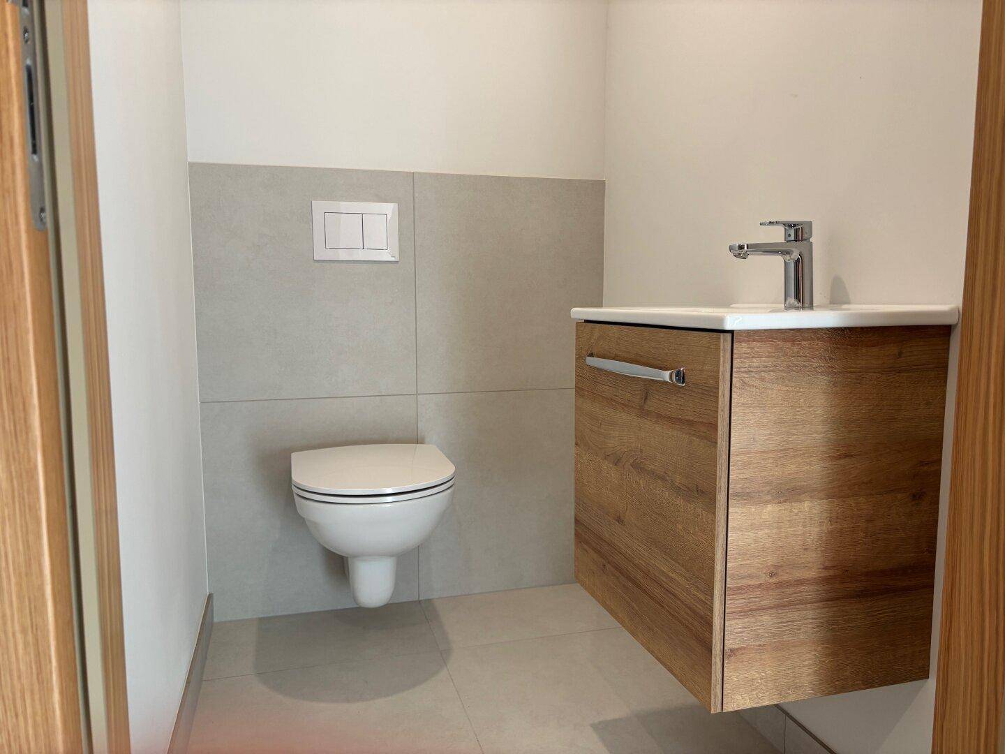 Modernes Gäste-WC mit wandhängendem WC und stilvollem Waschtischunterschrank aus Holz.