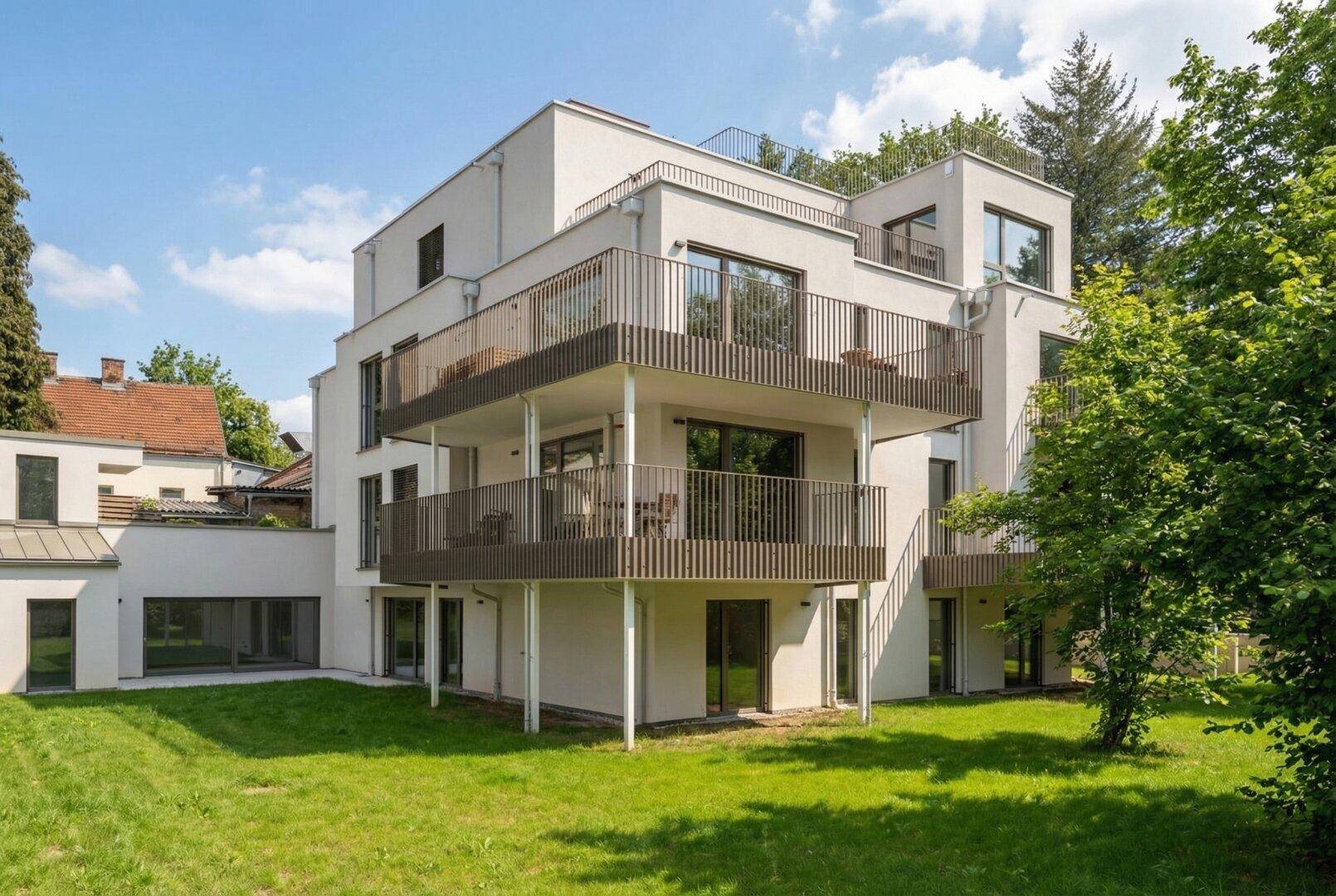 Ansicht des modernen Neubaus mit mehreren Balkonen und gepflegtem Rasenbereich.