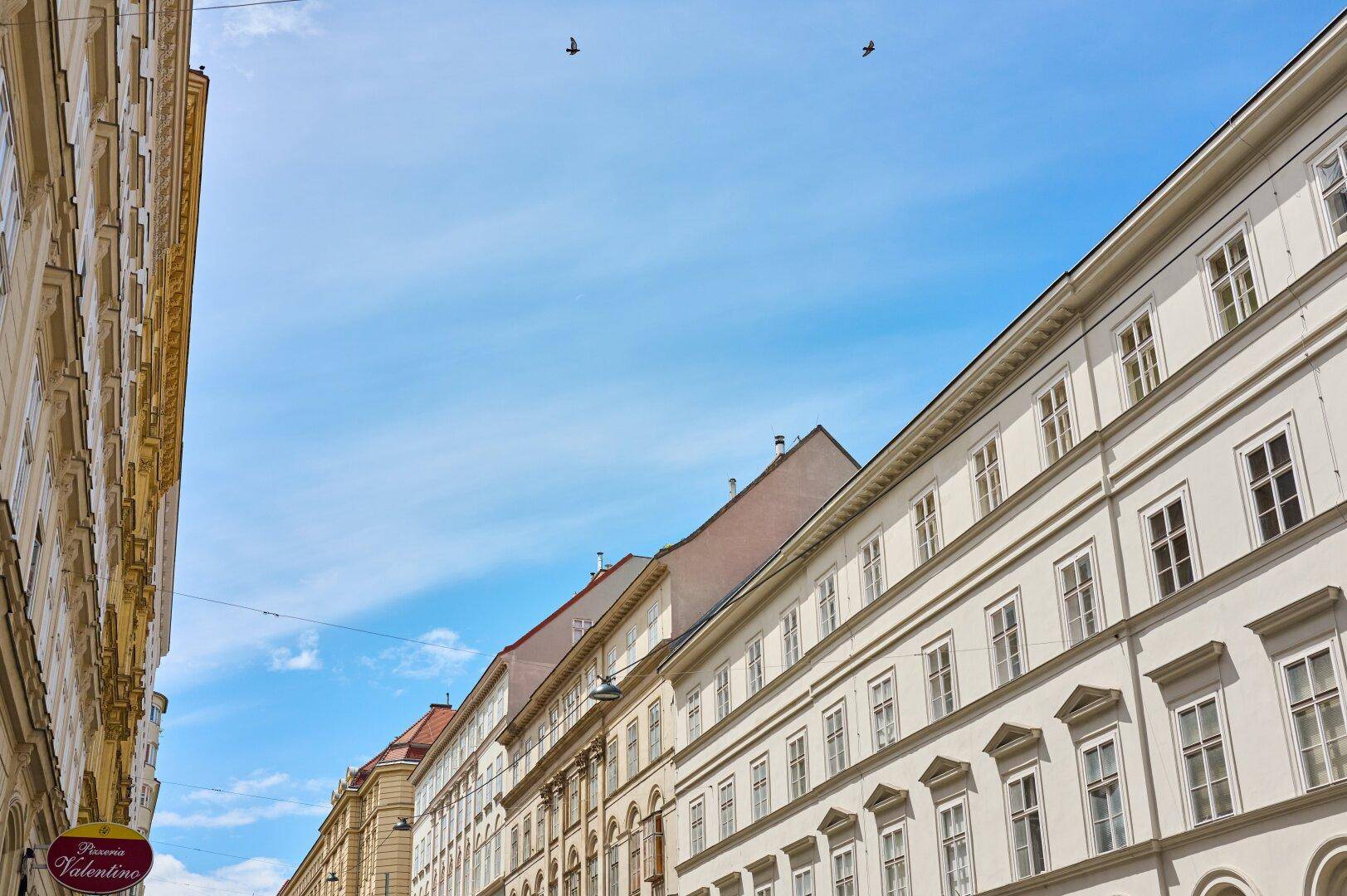 Historische Gebäude mit vielen Fenstern unter einem klaren blauen Himmel in der Stadt.