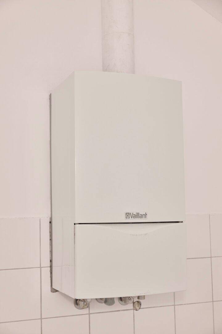 Gastherme von Vaillant an einer weiß gefliesten Wand in einem Hauswirtschaftsraum.