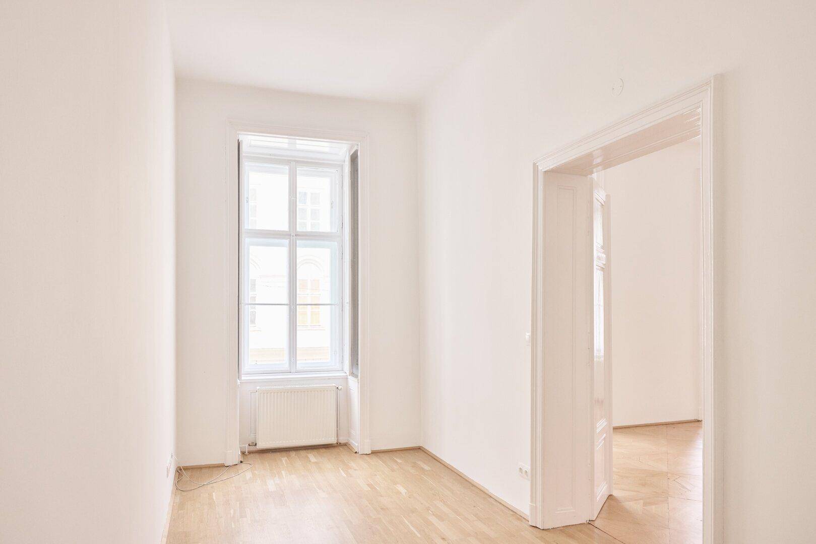 Heller, kleiner Raum mit einem Fenster und Holzboden, ideal als Schlaf- oder Arbeitszimmer.