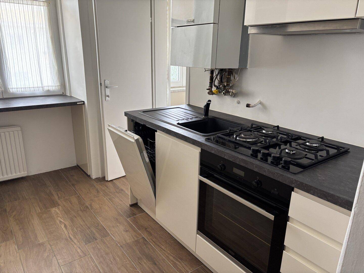 Moderne Küche mit Gasherd, Backofen, Spülmaschine und Hängeschränken, ausgestattet mit einem Boiler.