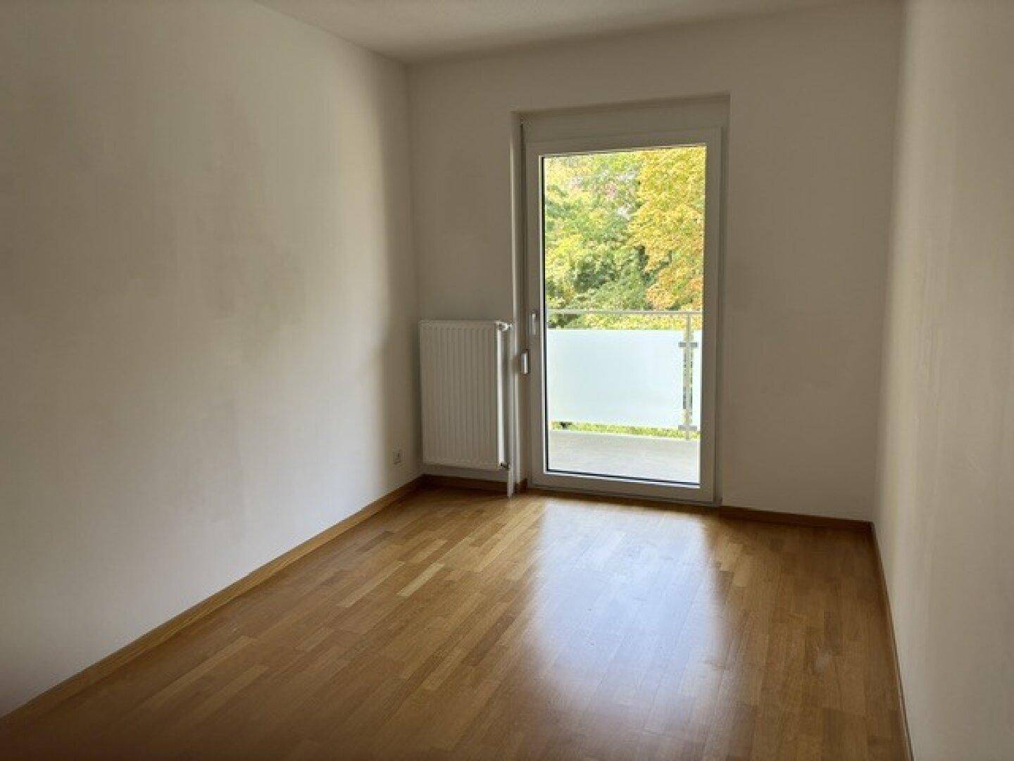 Gemütliches Schlafzimmer mit Parkettboden und direktem Zugang zu einem Balkon.