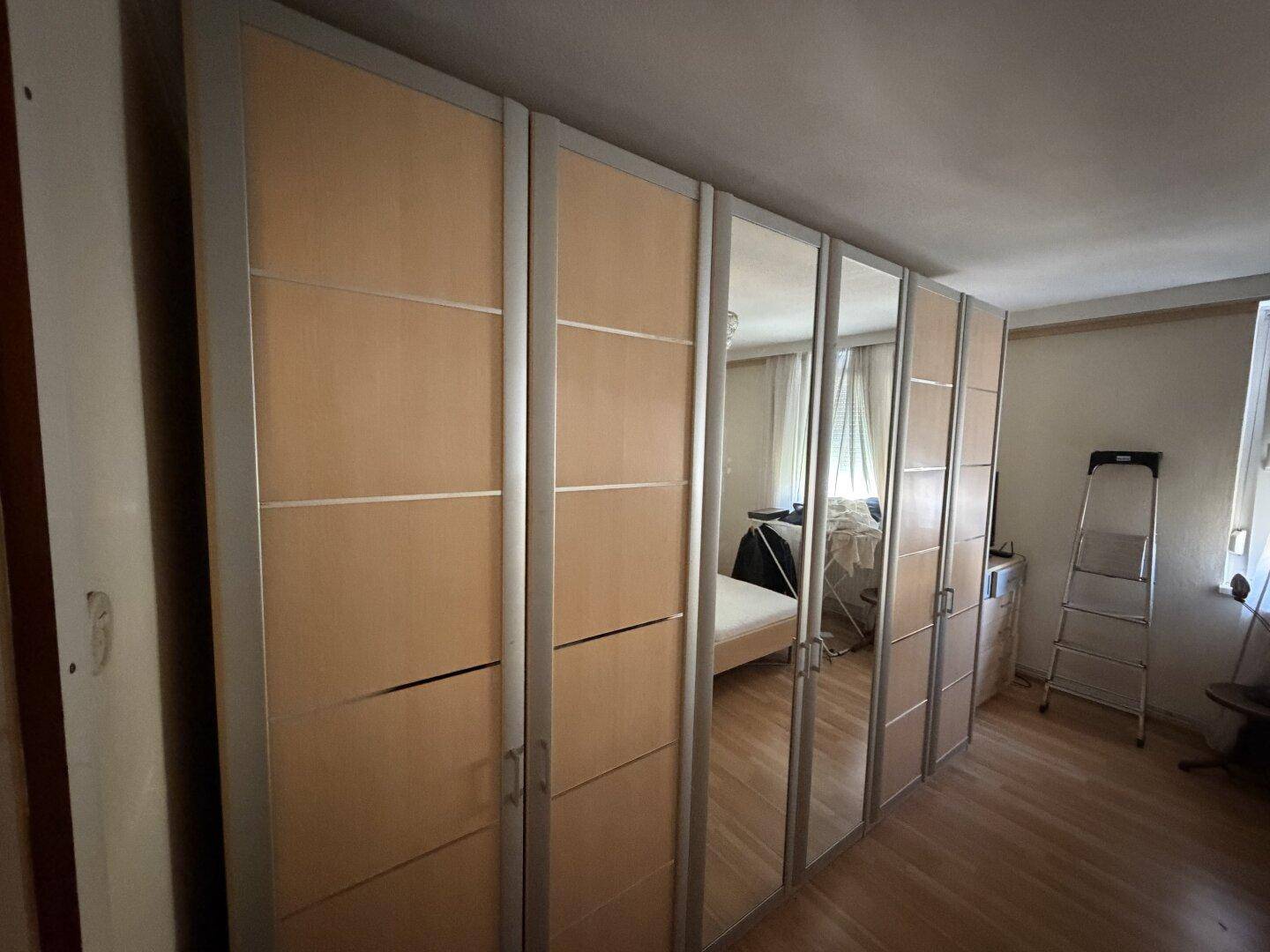 Schlafzimmer mit großen Spiegelschränken und Holzboden, der das Licht reflektiert.