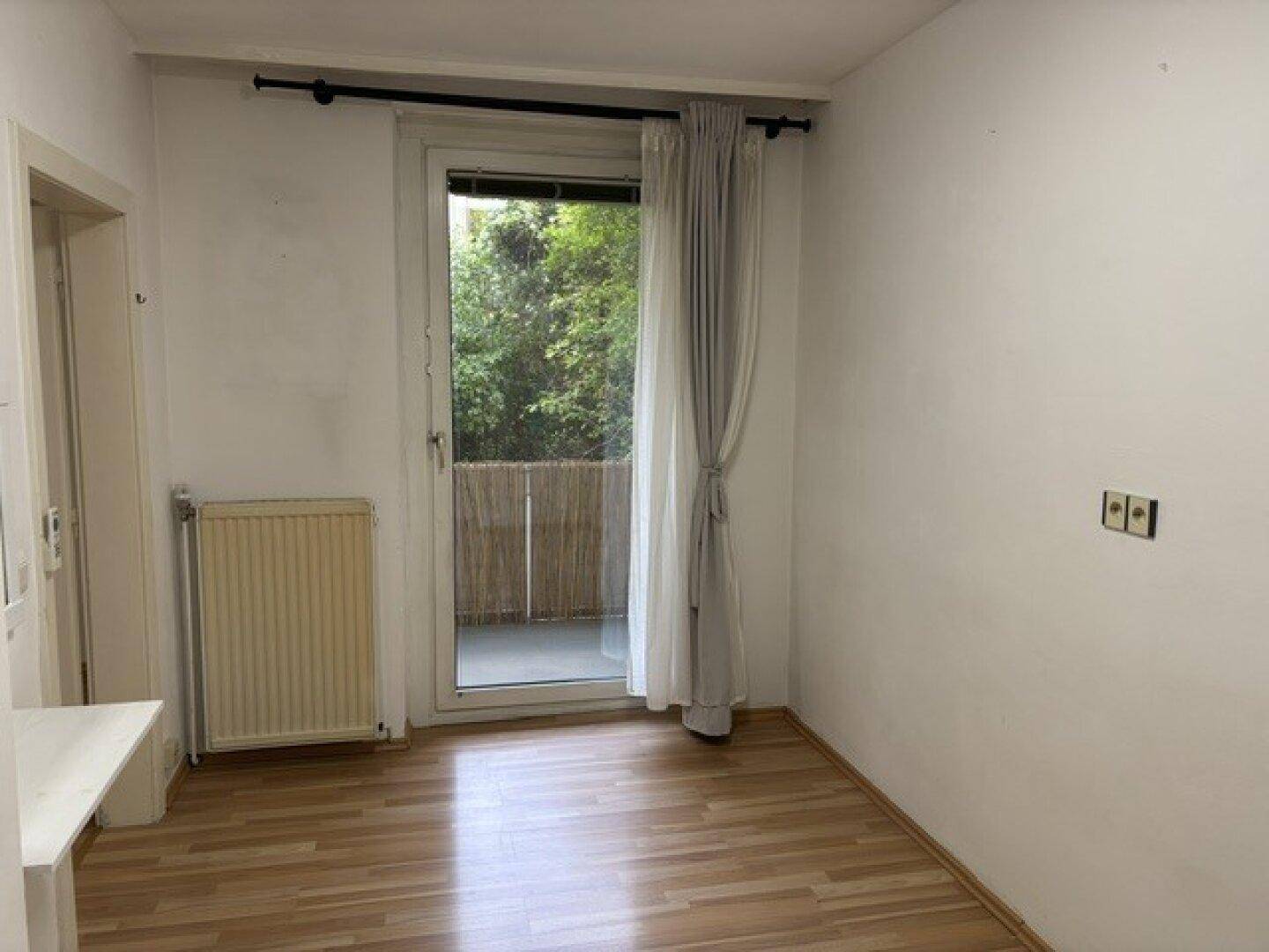 Helles Zimmer mit Laminatboden und direktem Zugang zu einem kleinen Balkon, ideal für frische Luft.