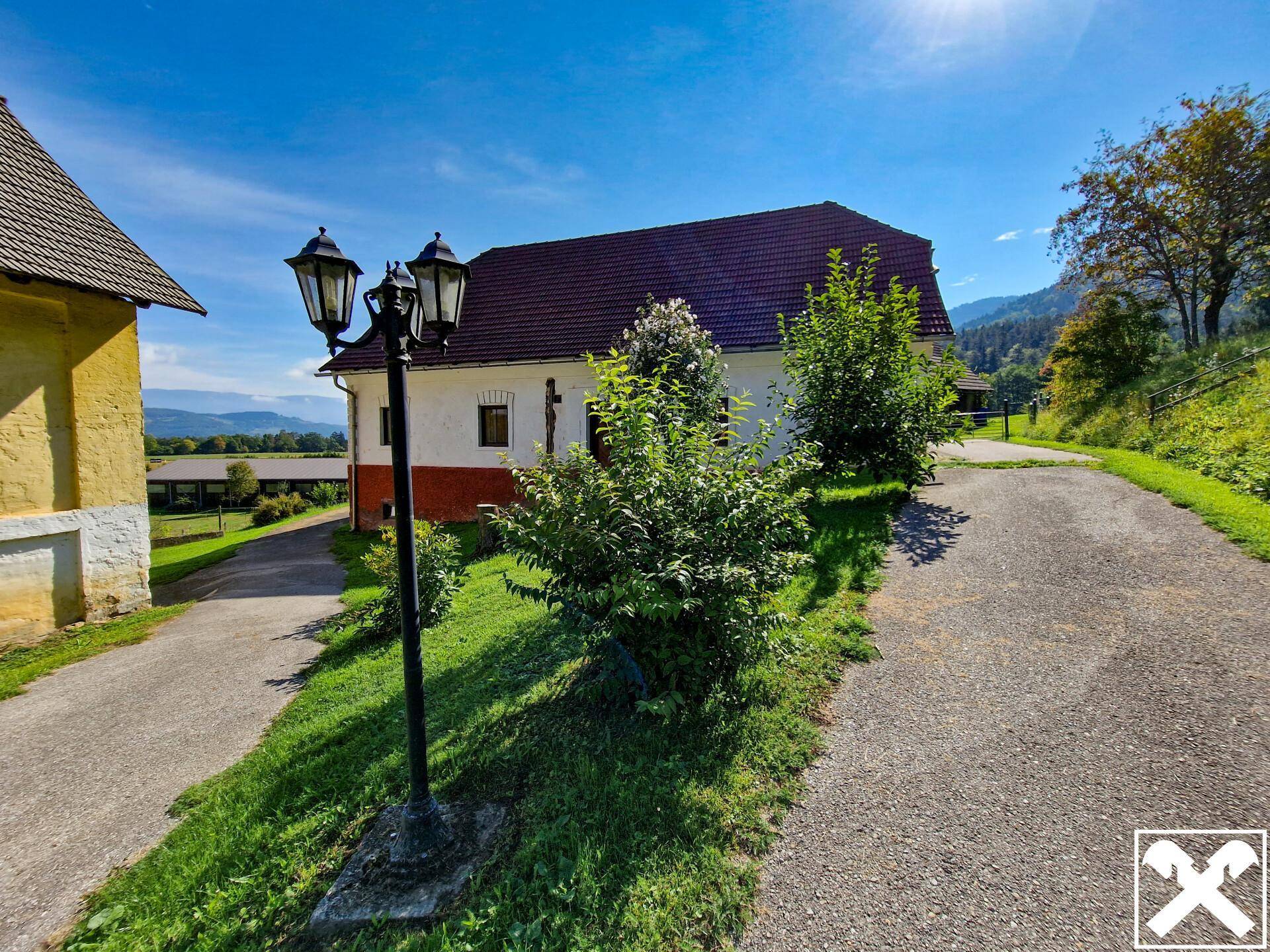 Historisches Landhaus mit Laternenpfahl und Blick auf die umliegende Natur und Berge.