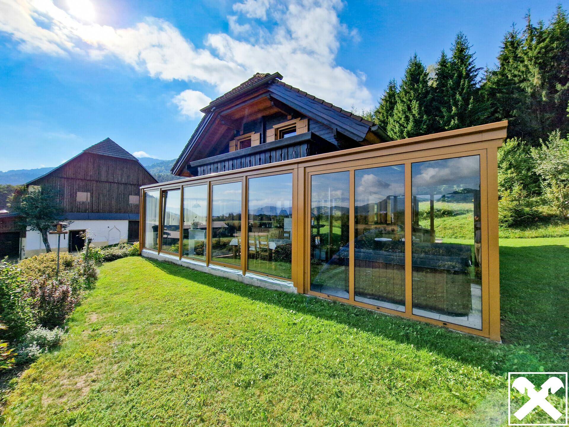 Moderner Wintergarten am Holzhaus mit großen Glasfronten, Blick ins Grüne und Whirlpool.