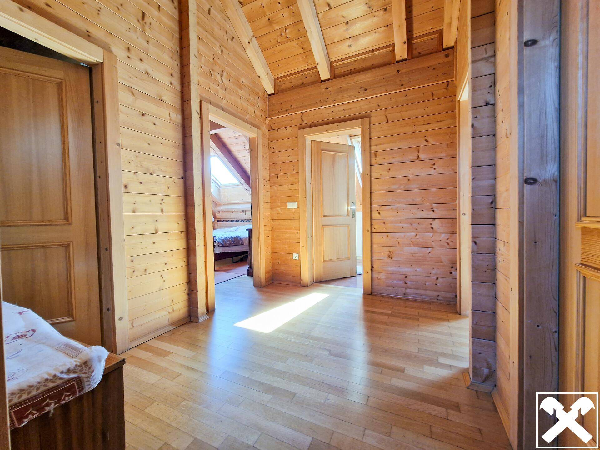Heller Flur mit Holztäfelung, Holzboden und Zugang zu mehreren Zimmern im Dachgeschoss.