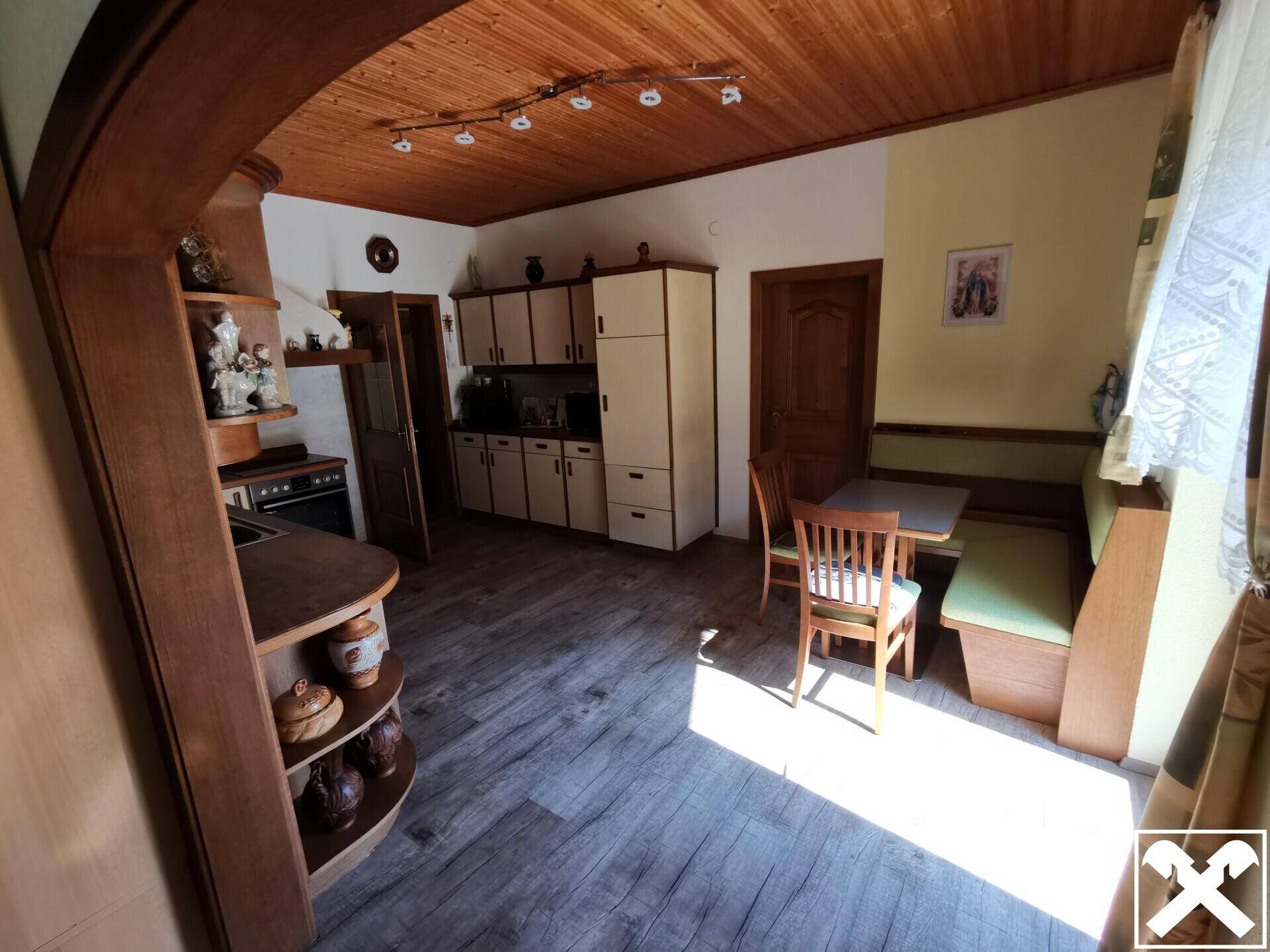 Helle Küche mit Essbereich, Holzdecke und Zugang zu weiteren Räumen.