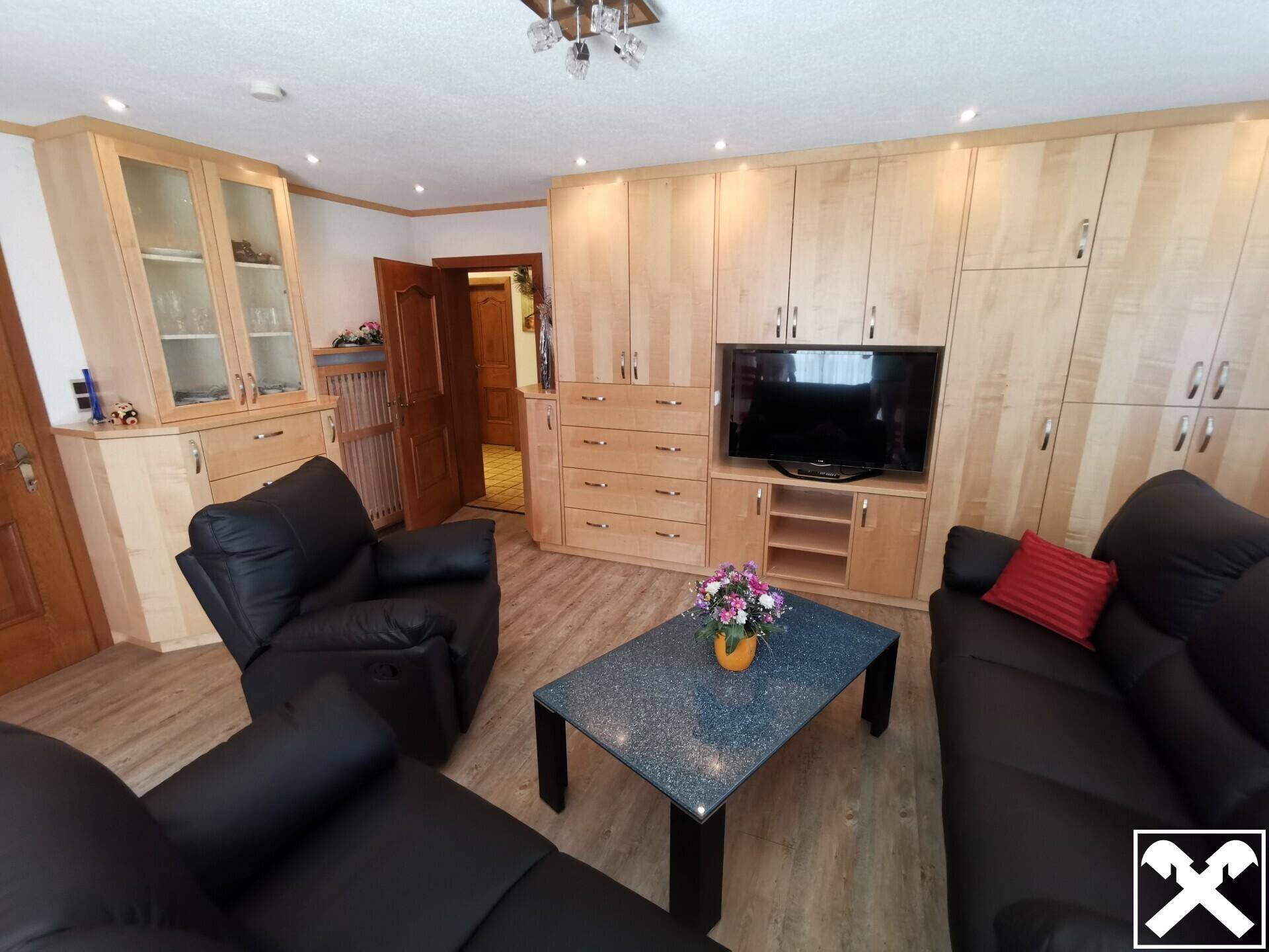 Wohnzimmer mit bequemen Ledersofas, Einbauschränken und hellem Holzdekor.