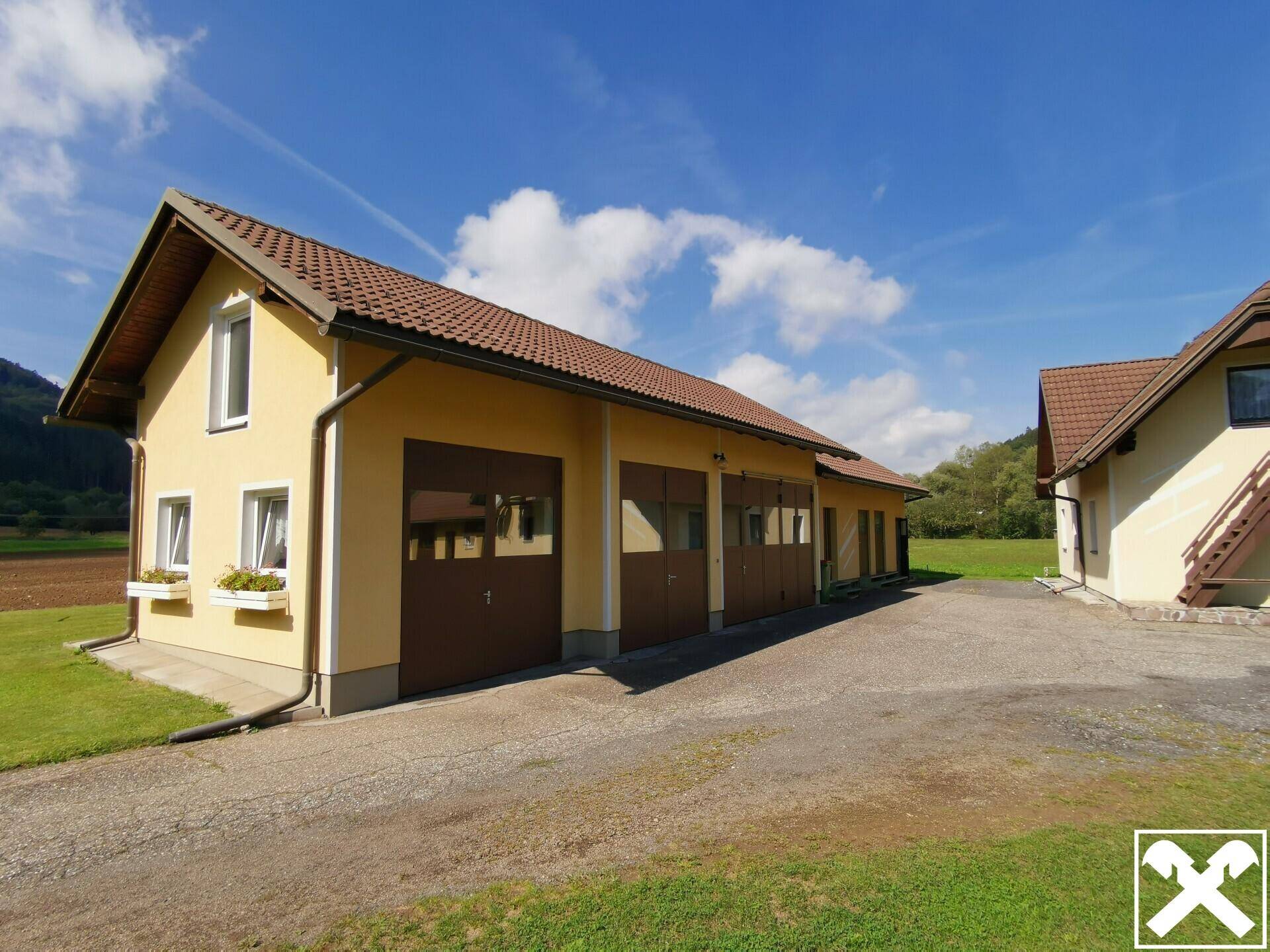 Geräumiges Garagengebäude mit mehreren Toren und gelber Fassade auf dem Land.