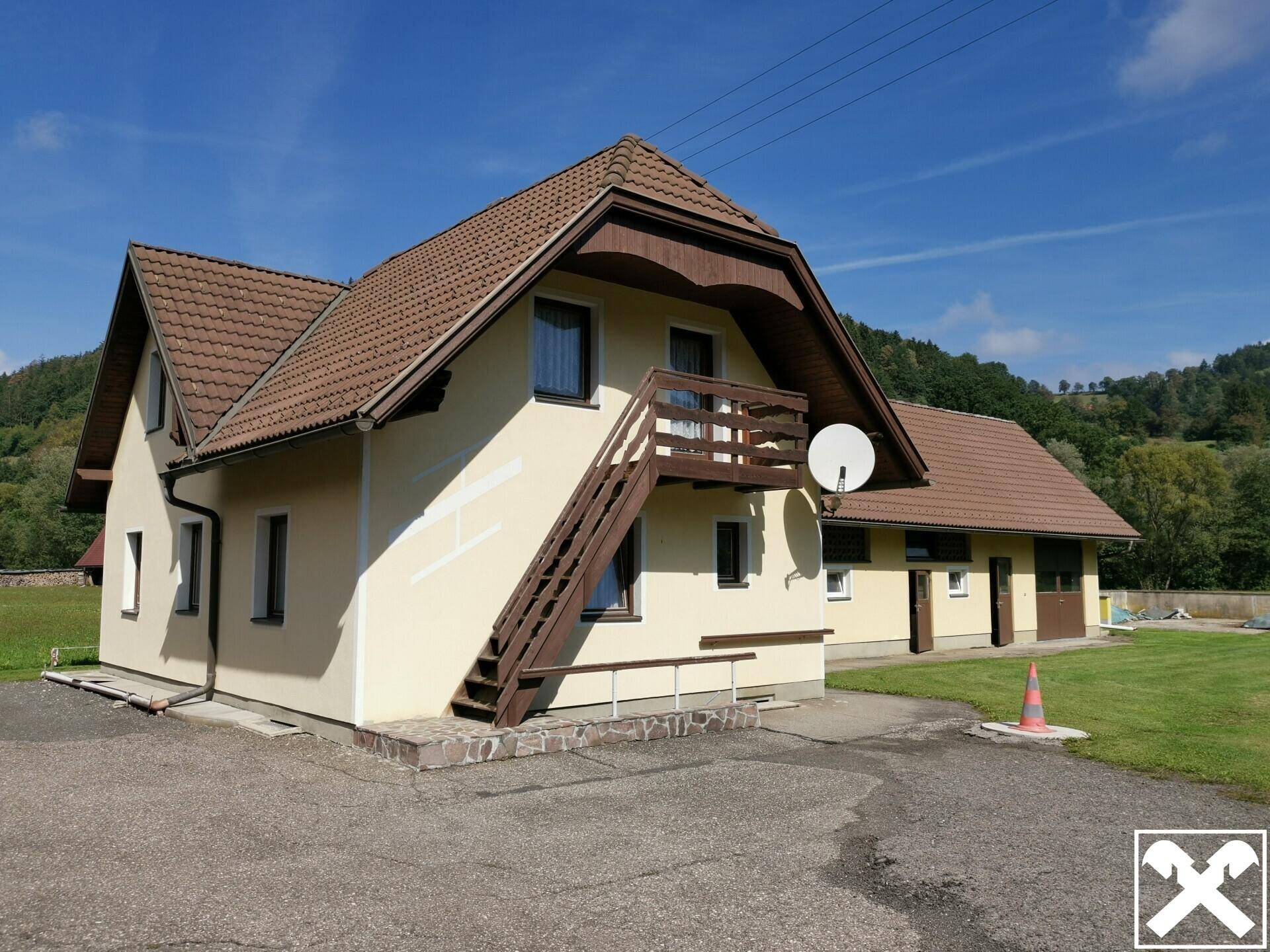 Nebengebäude mit braunem Ziegeldach und Außentreppe in ländlicher Umgebung.