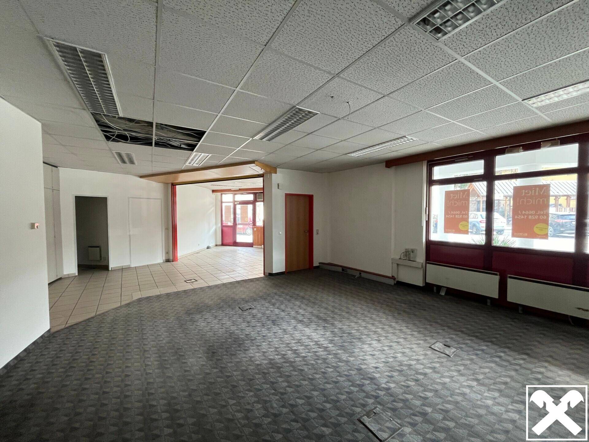 Großer, leerer Gewerberaum mit Teppichboden und Fliesen, bereit für den individuellen Ausbau.