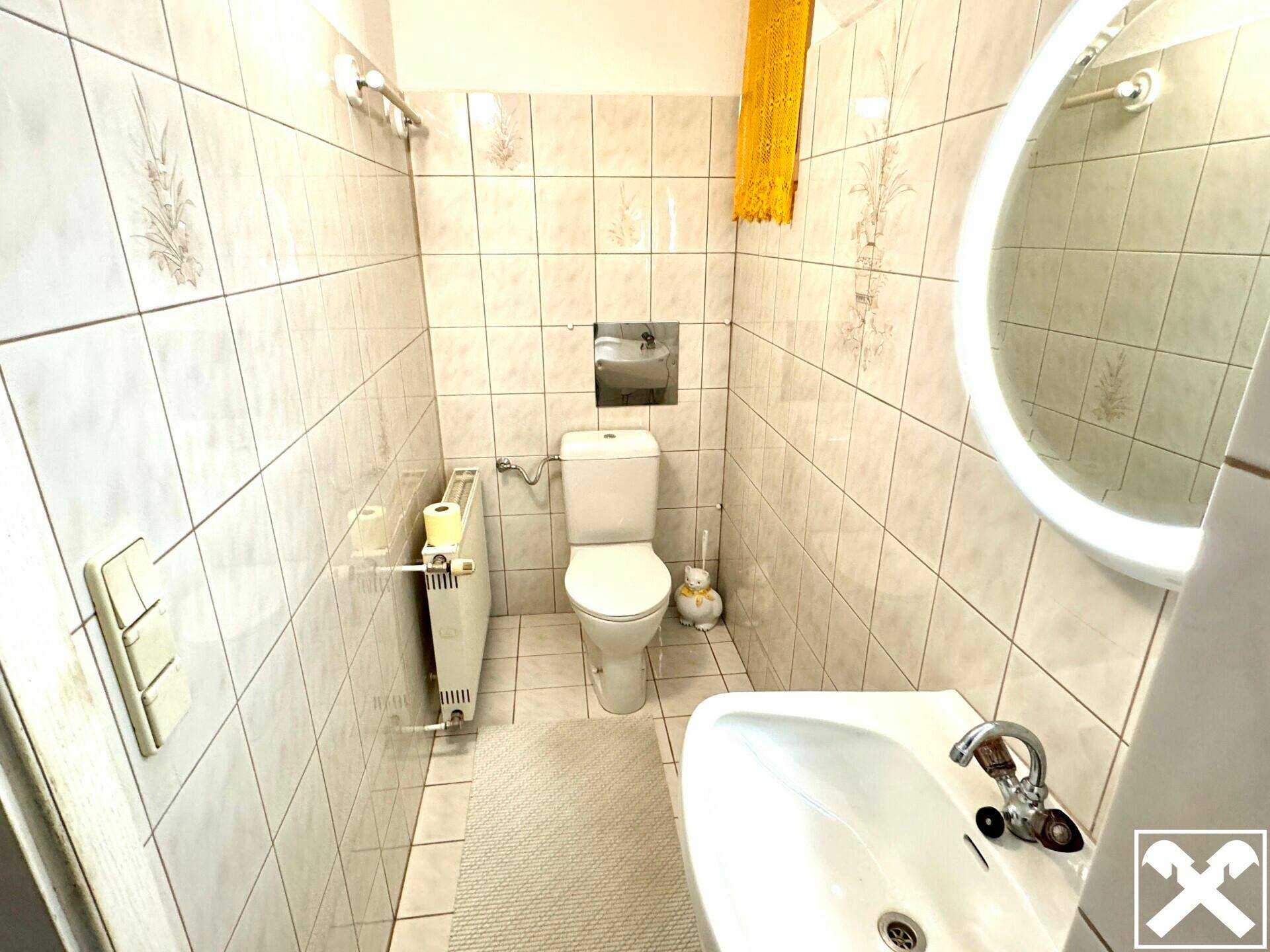Kleines Gäste-WC mit Fliesen, Waschbecken und Toilette.