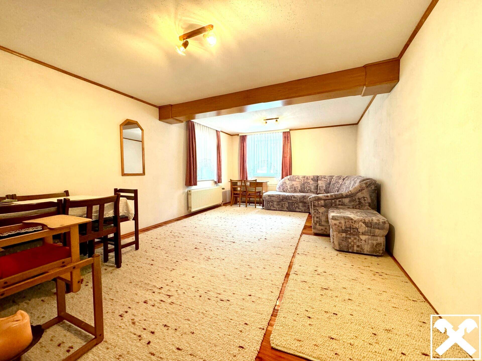 Gemütliches Wohnzimmer mit Teppichboden, Sofa und Esstisch in traditionellem Stil.