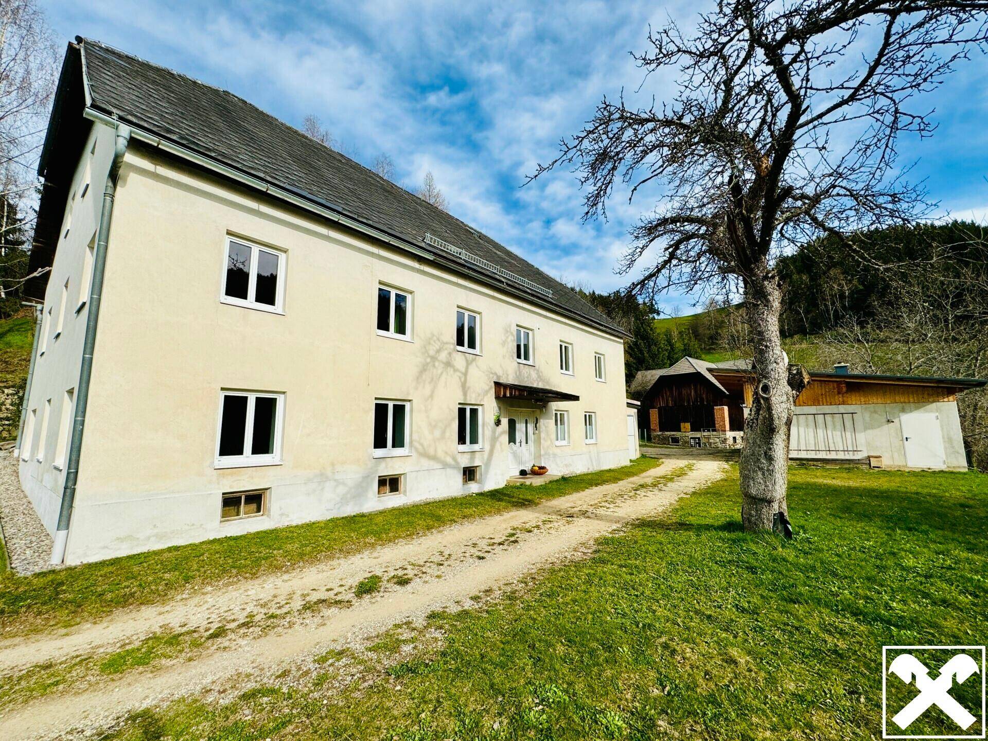 Vorderansicht des gepflegten Wohnhauses mit Zufahrt und weitläufiger Grünfläche.