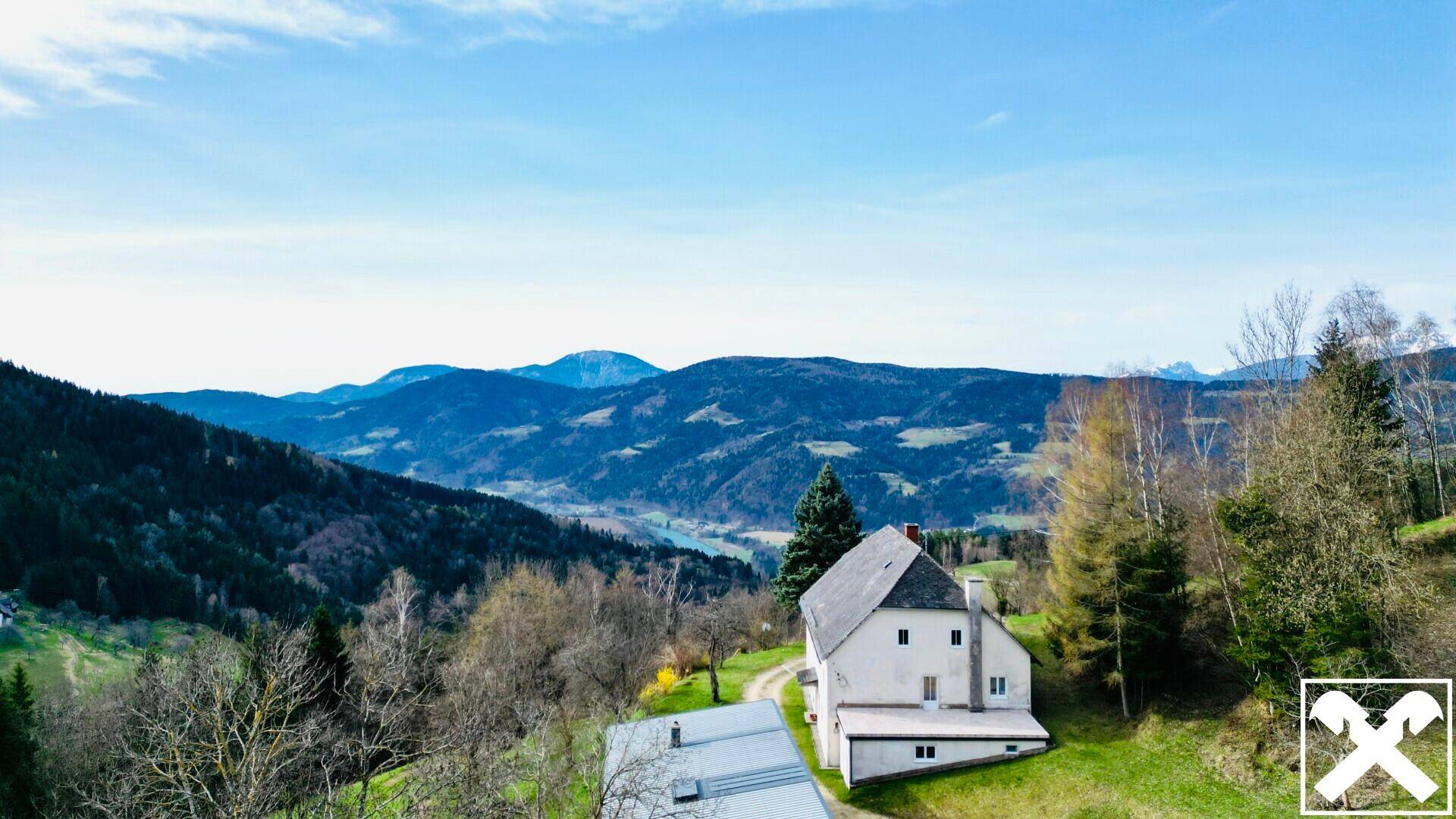 Luftaufnahme des Anwesens mit Haupthaus und weitem Blick auf die umliegende Berglandschaft.