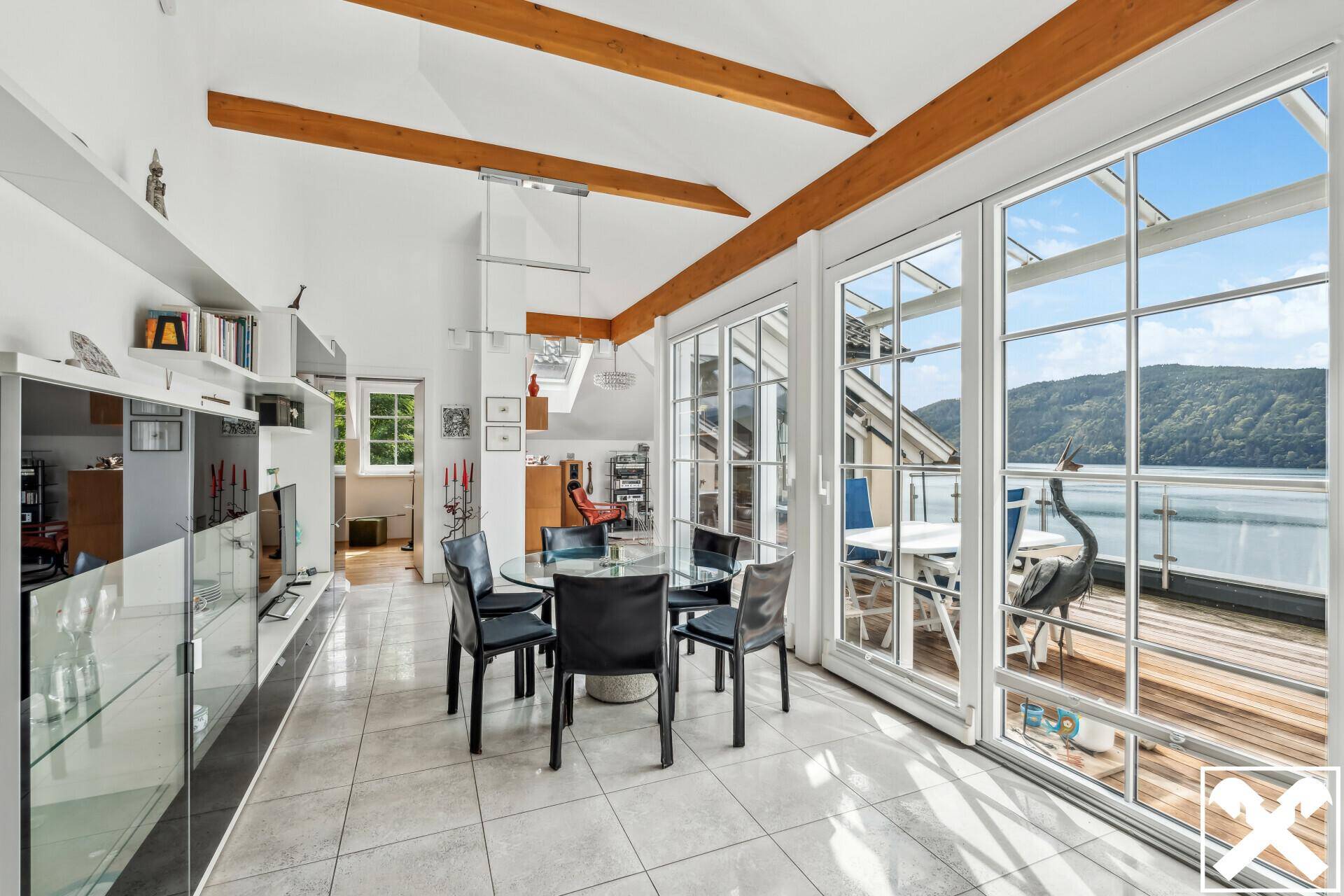 Geräumiger Wohn-Essbereich mit großen Fenstern, die einen weiten Blick auf den See bieten.