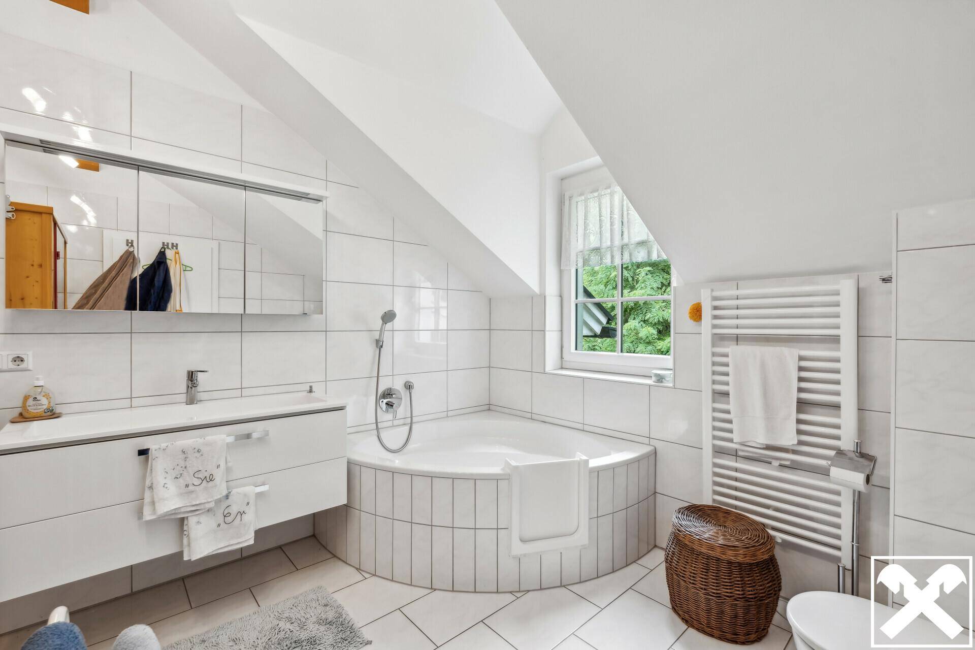 Helles Badezimmer mit Eckbadewanne, modernem Waschtisch und beheiztem Handtuchhalter.