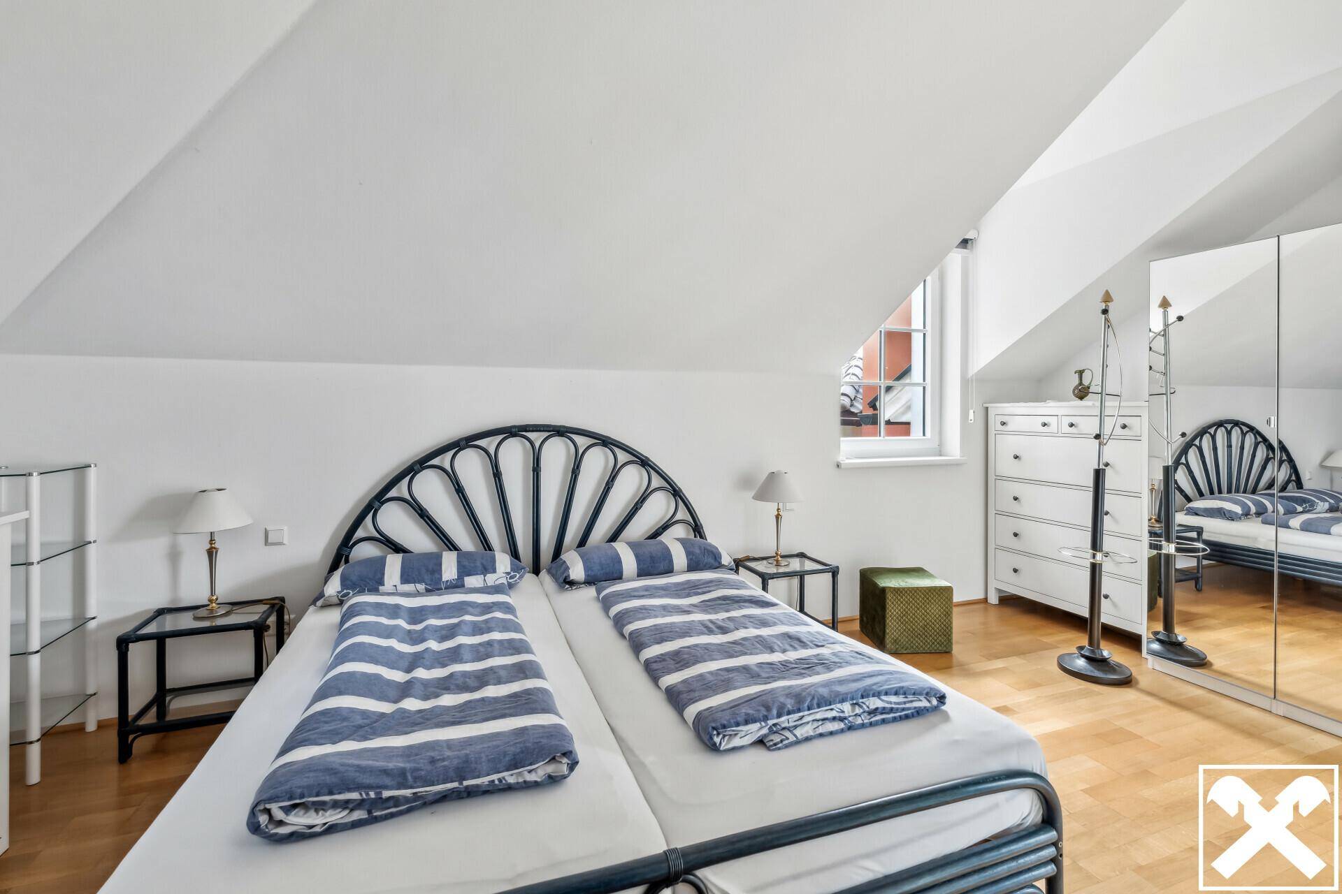 Gemütliches Schlafzimmer mit Holzboden, Dachschräge und großem Spiegelschrank.