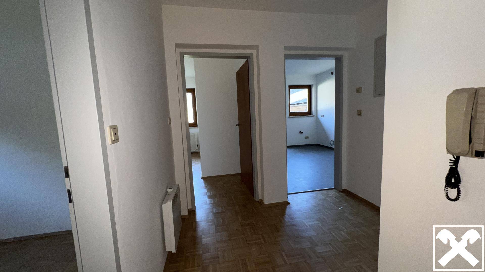 Heller Flur mit Parkettboden und Zugängen zu mehreren Zimmern, ausgestattet mit einer Gegensprechanlage.