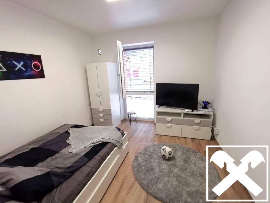 Jugendzimmer mit Einzelbett, Schrank und Fernseher, ausgestattet mit Holzoptikboden.