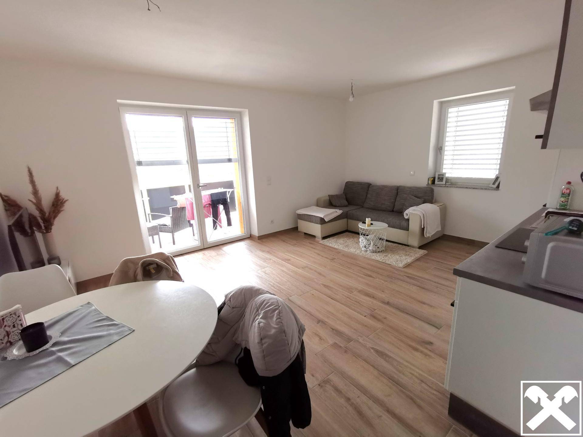 Heller Wohn- und Essbereich mit Holzoptikboden und Zugang zu einem Balkon oder einer Terrasse.