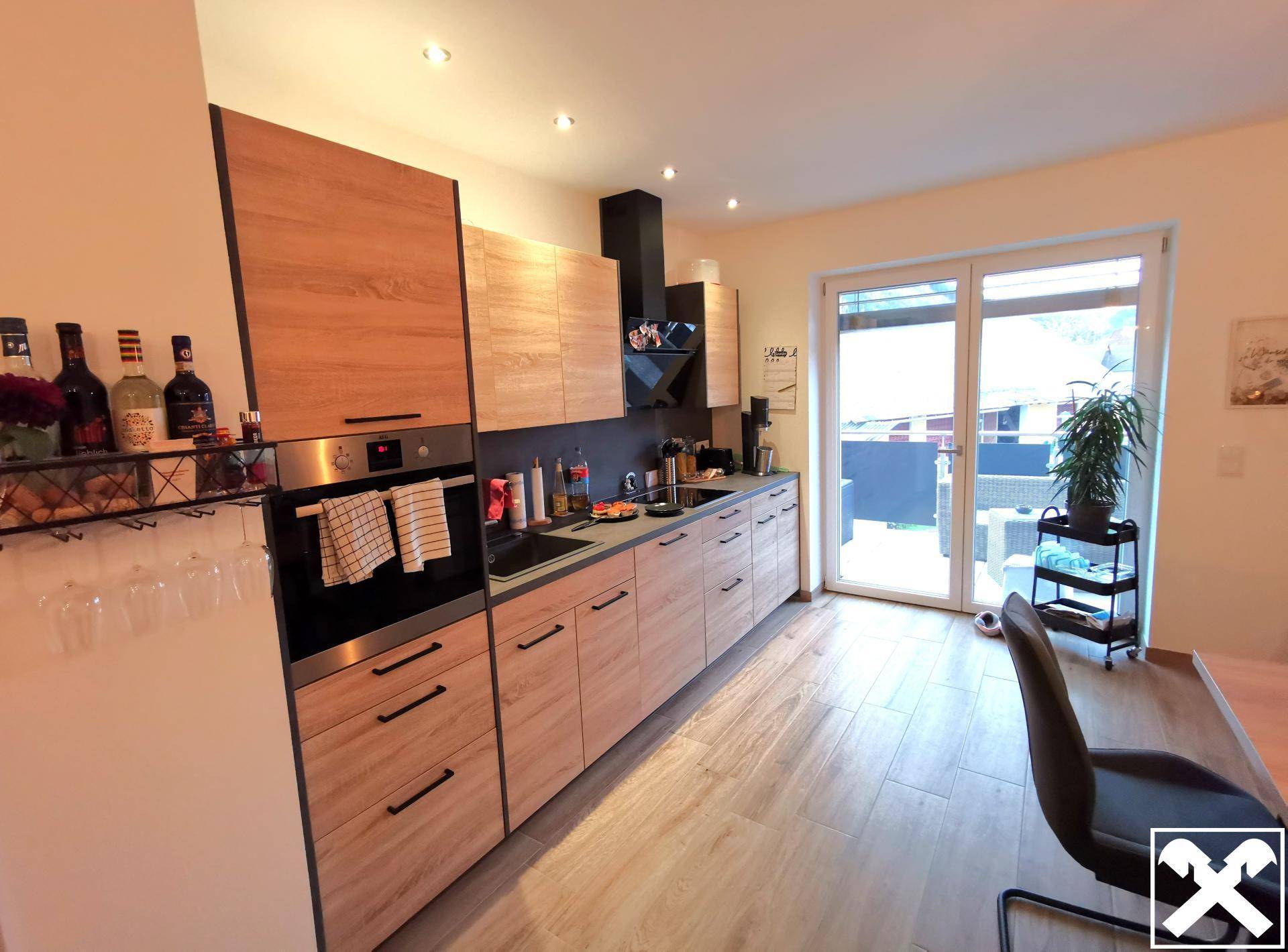 Moderne Holzküche mit integrierten Geräten und Zugang zu einem Außenbereich.