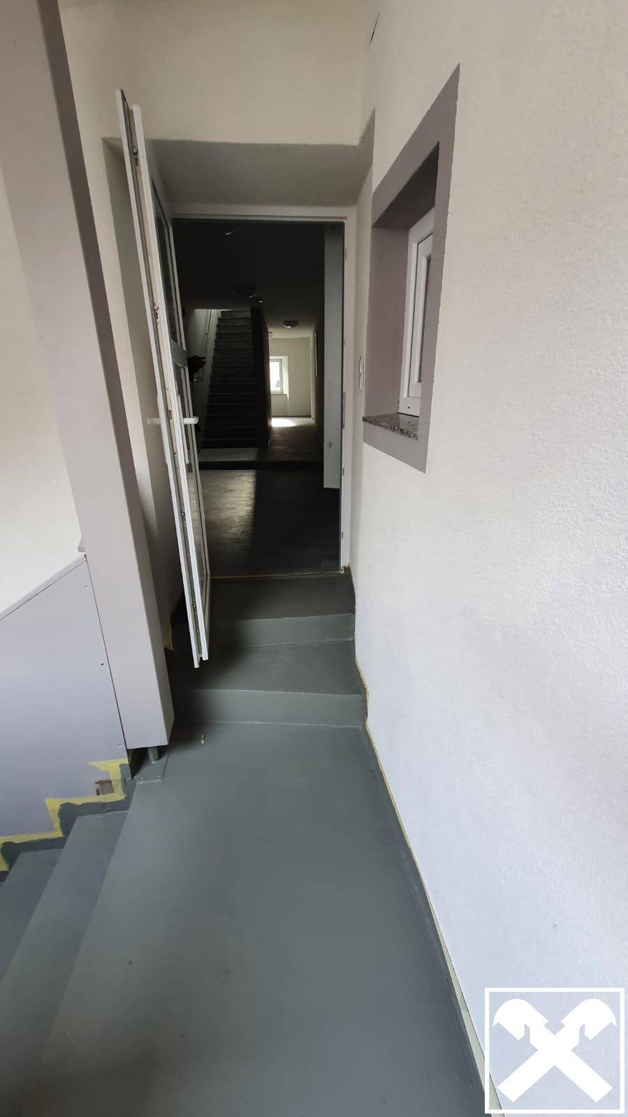 Treppenaufgang mit grauen Stufen und hellem Geländer, führt in die oberen Stockwerke des Hauses.