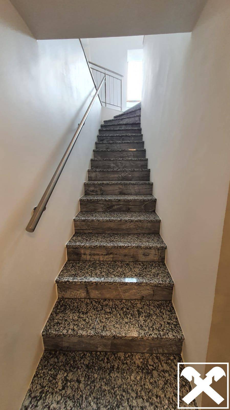 Treppenhaus mit Granitstufen und Metallgeländer, das zu den oberen Etagen des Gebäudes führt.