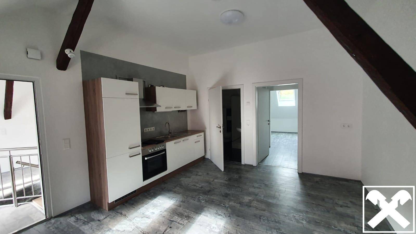 Helle Küche in einem Dachgeschoss-Apartment mit Holzbalken und modernem Laminatboden.