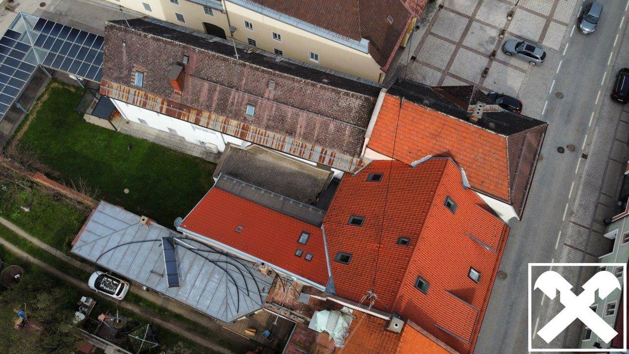 Vogelperspektive auf eine Ansammlung von Gebäuden mit roten Ziegeldächern und Straßen in der Stadt.