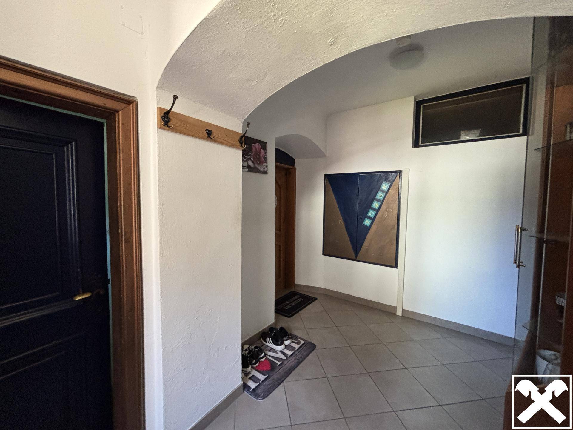 Heller Eingangsbereich mit Fliesenboden, Garderobe und dekorativer Wandkunst.