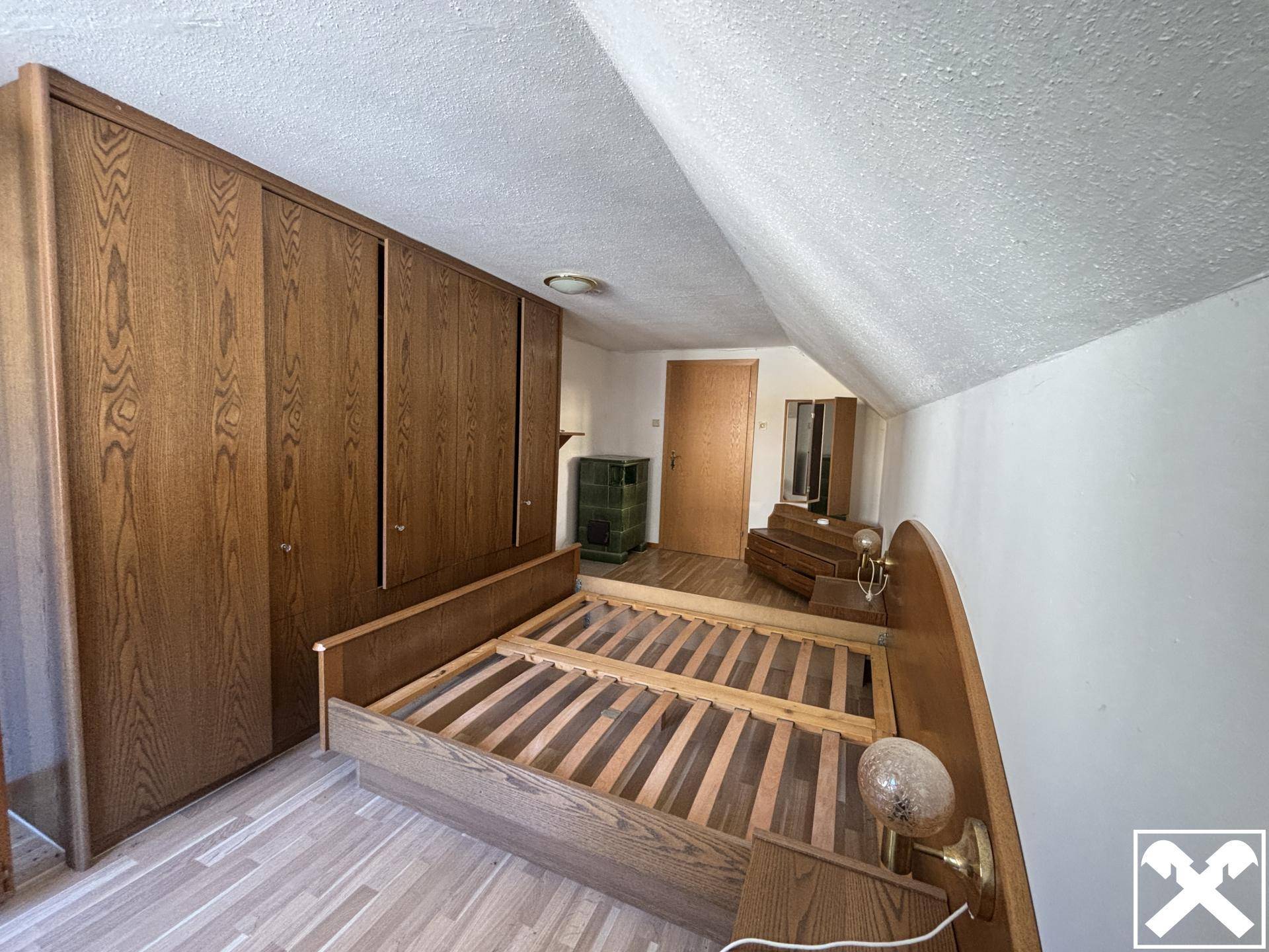 Schlafzimmer mit Holzbett, Einbauschränken und Dachschräge.