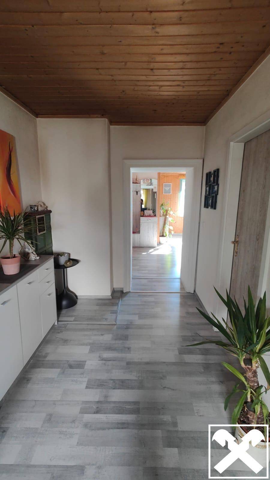 Heller Flur mit Holzdecke, modernem Laminatboden und Pflanzen.