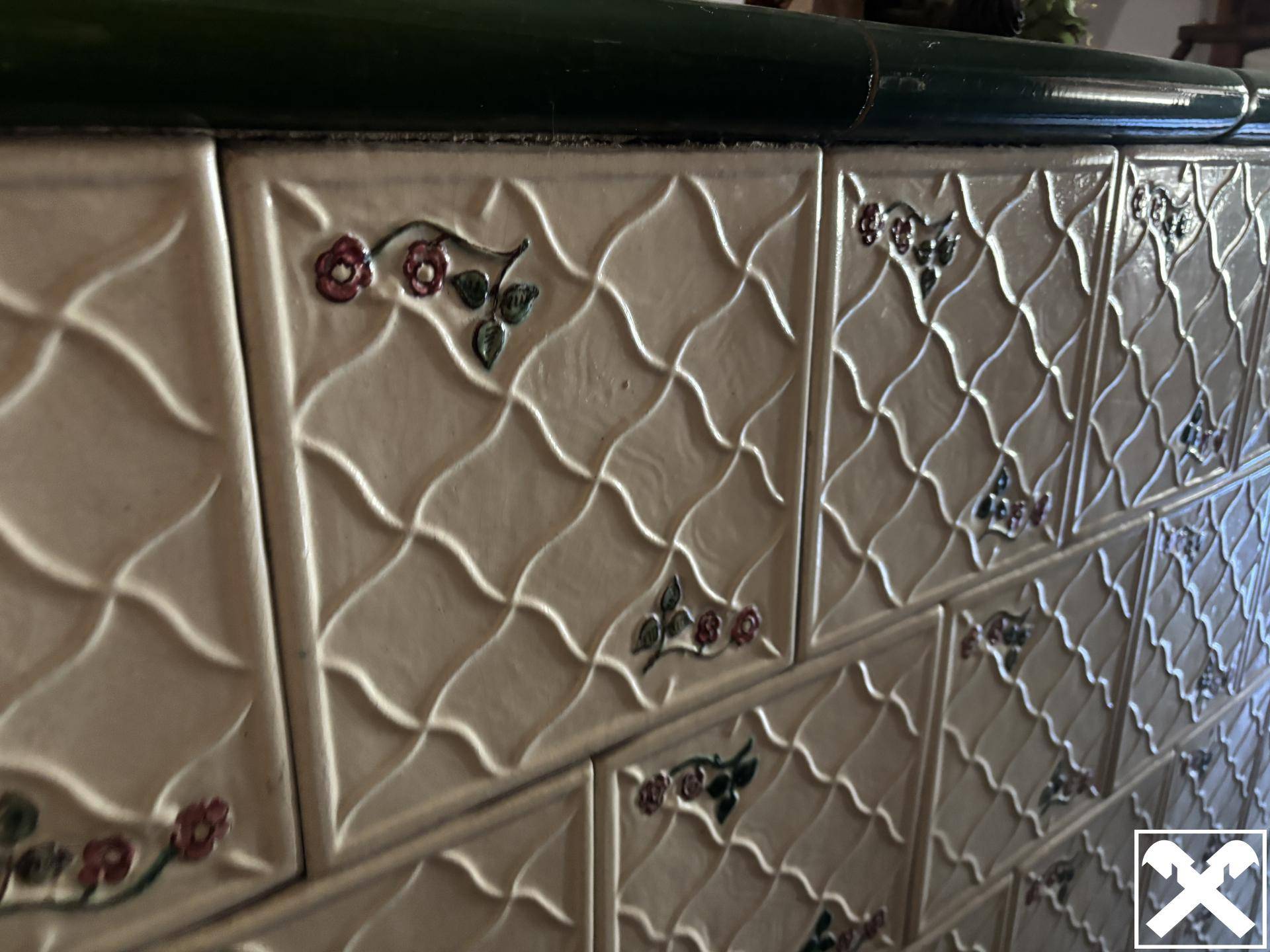 Nahaufnahme eines traditionellen Kachelofens mit detailreichen floralen Verzierungen.