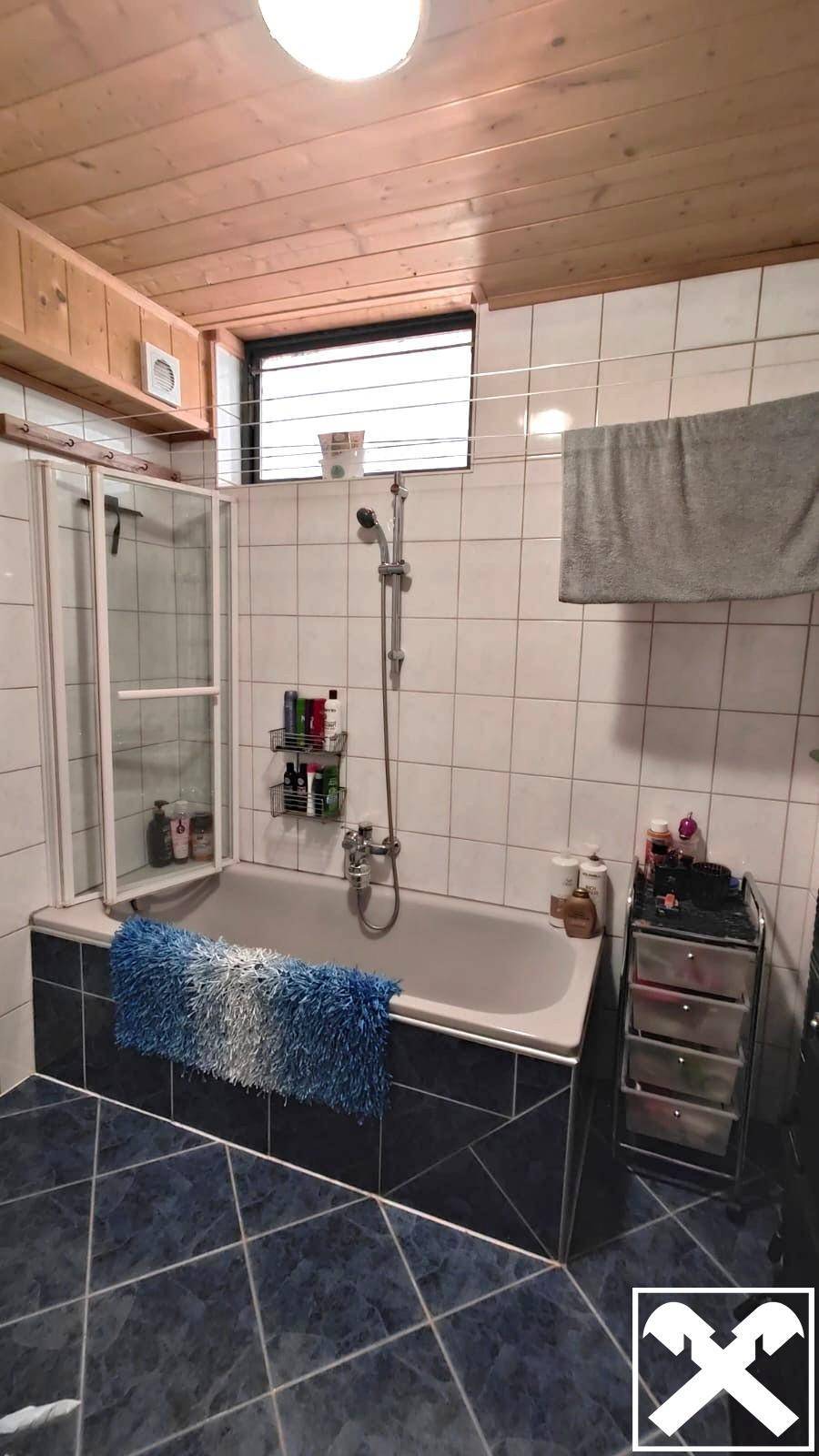 Badezimmer mit Badewanne, Dusche, Fliesen und Holzdecke.