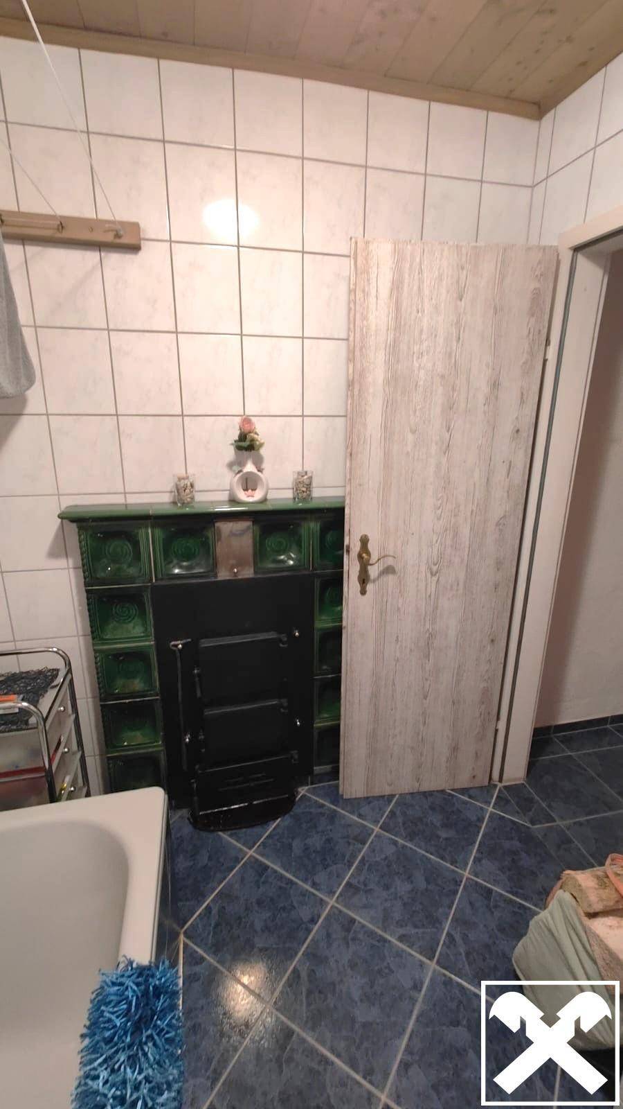 Badezimmer mit blauen Fliesen, Holzdecke und einem traditionellen Ofen.